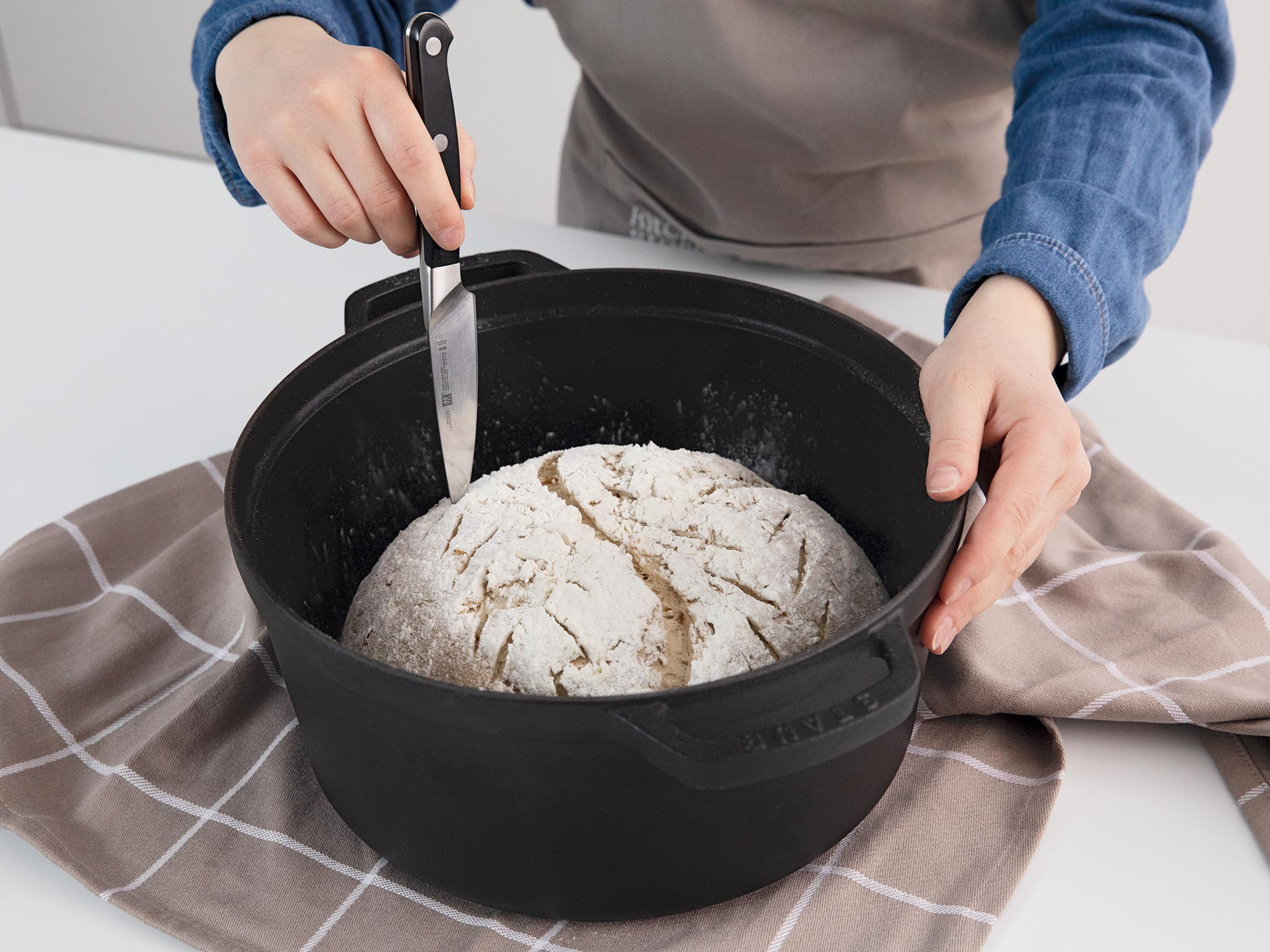 Um das gegangene und geformte Brot richtig einzuschneiden, verwende ein kleines, scharfes Messer, eine Rasierklinge oder ein Skalpell. Das Einkerben hilft dem Brot dabei, gleichmäßig und schön aufzugehen, anstatt an den Nähten aufzureißen. Backe das Brot direkt nach dem einschneiden.