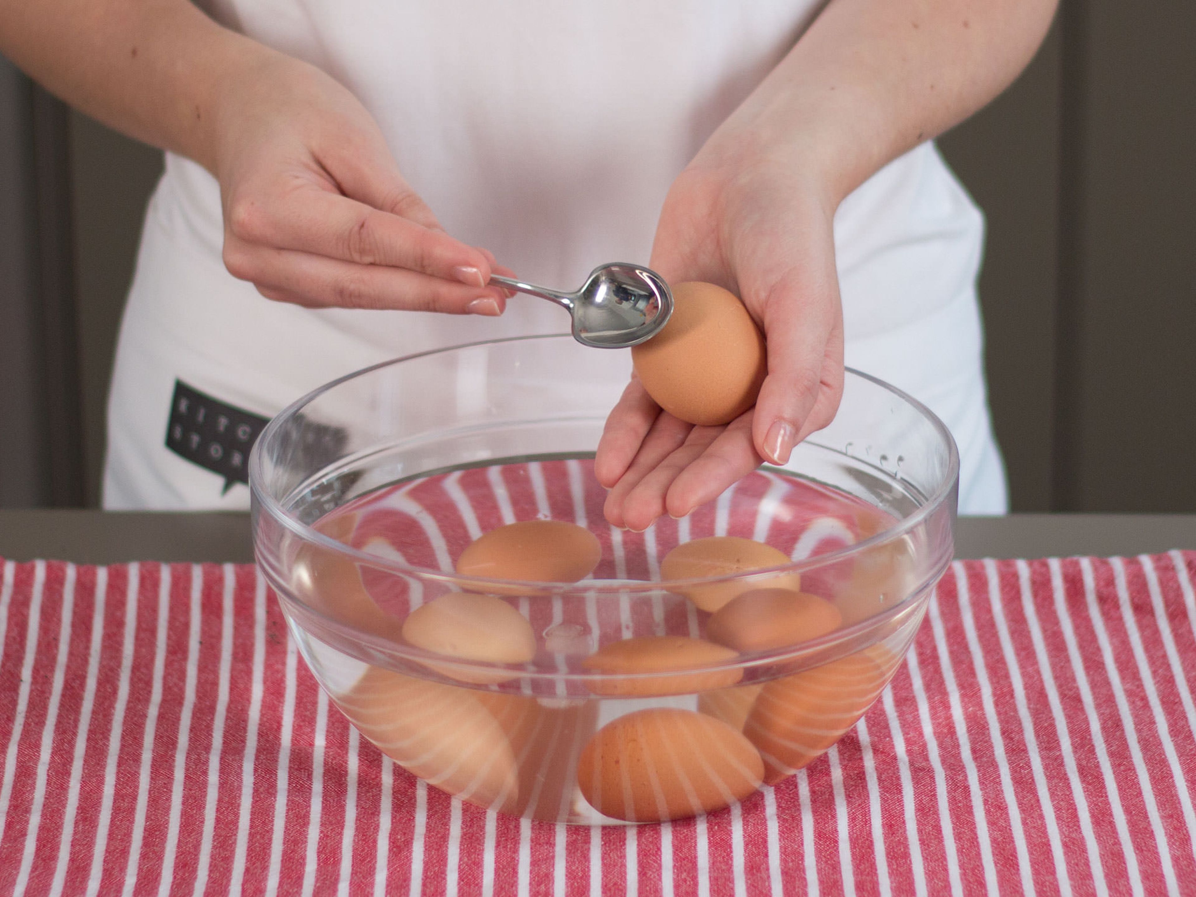 Die Schalen der abgekühlten Eier mit einem Löffel rundherum vorsichtig anschlagen.