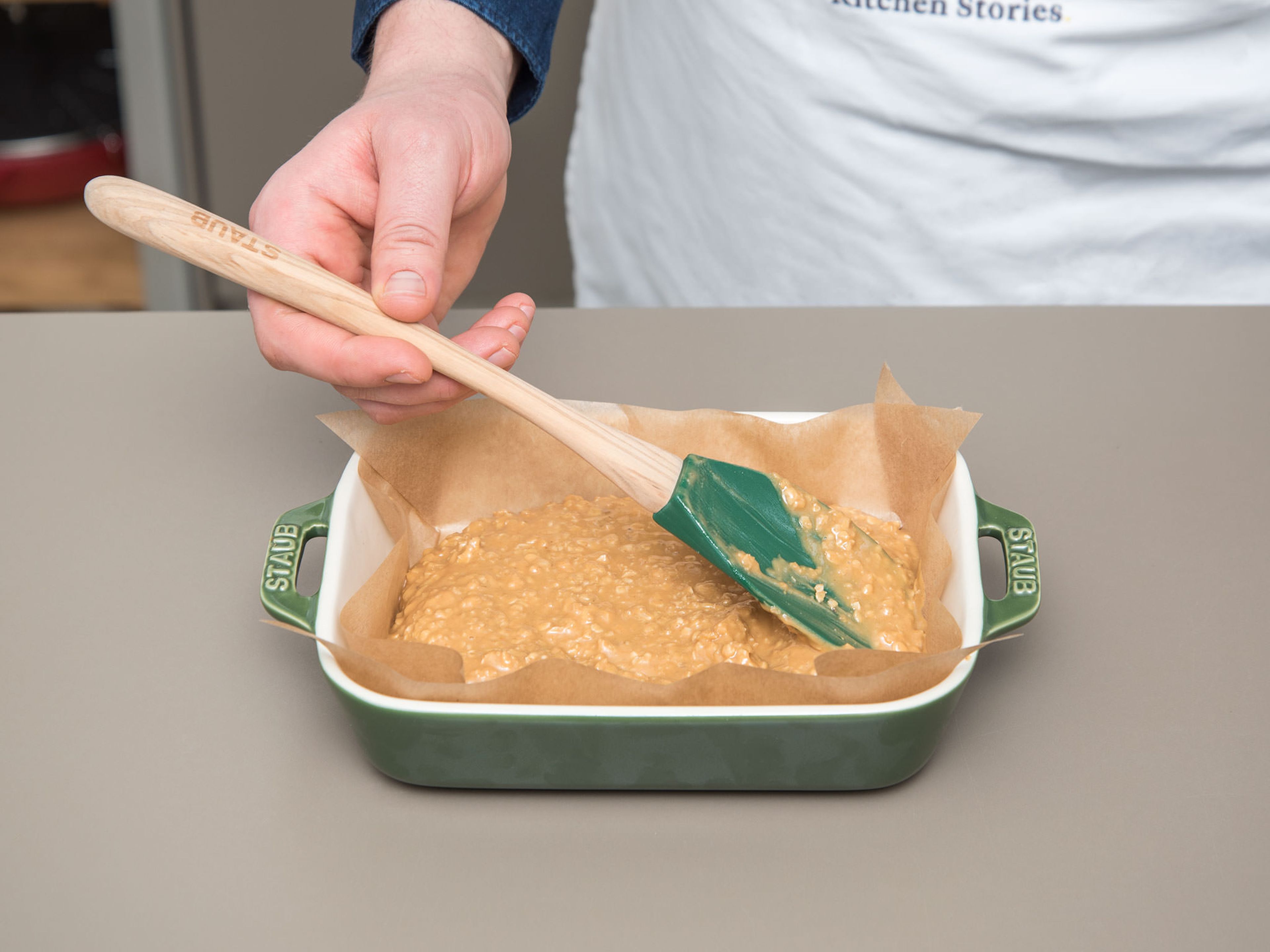 Line the baking dish with parchment paper and spread the peanut butter oat mixture evenly into the bottom of the dish with the rubber spatula. Press firmly. Freeze for approx. 20 min.