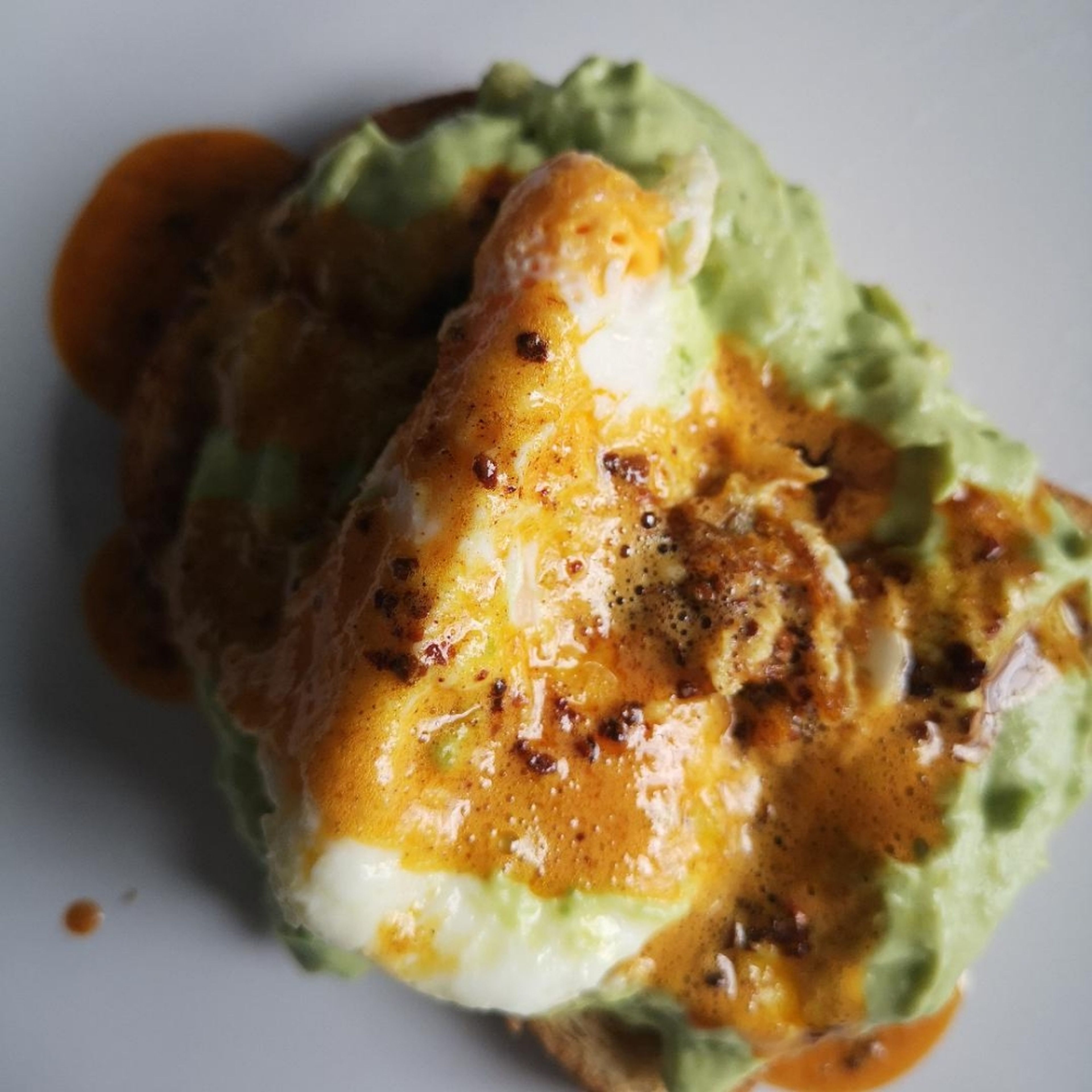 assemble your dish by spreading the avocado onto the toast, making a small hole for the egg and placing it inside. Finish by spooning the chili butter on top.