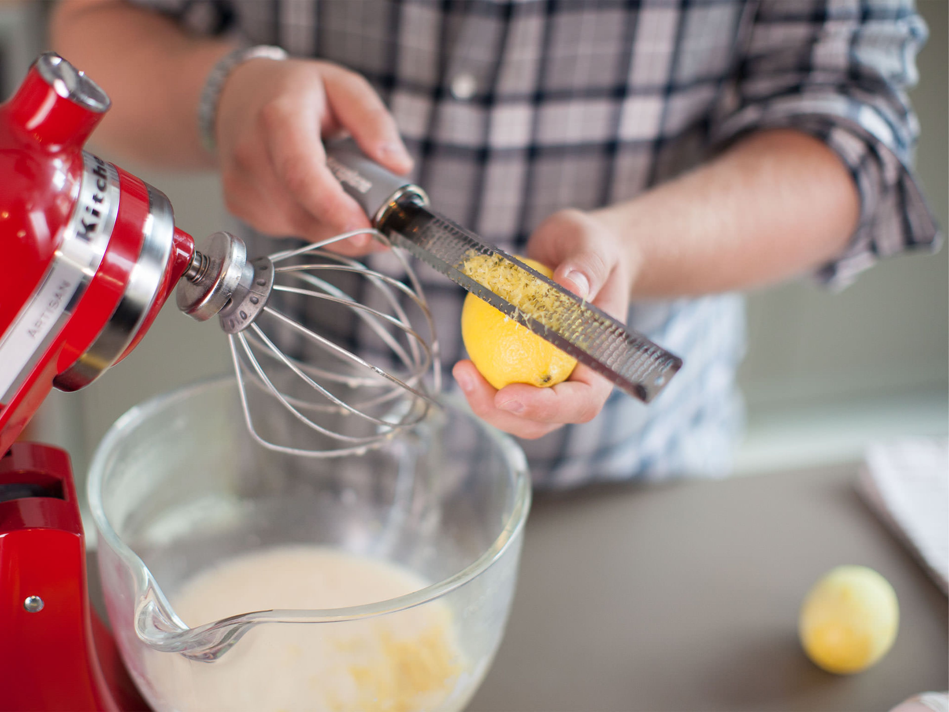 Restliche Eier und Zucker in einer Küchenmaschine schaumig aufschlagen. Mascarpone, Sahne und Zitronenabrieb hinzugeben. Zitronen auspressen und einen Teil des Saftes hinzufügen.