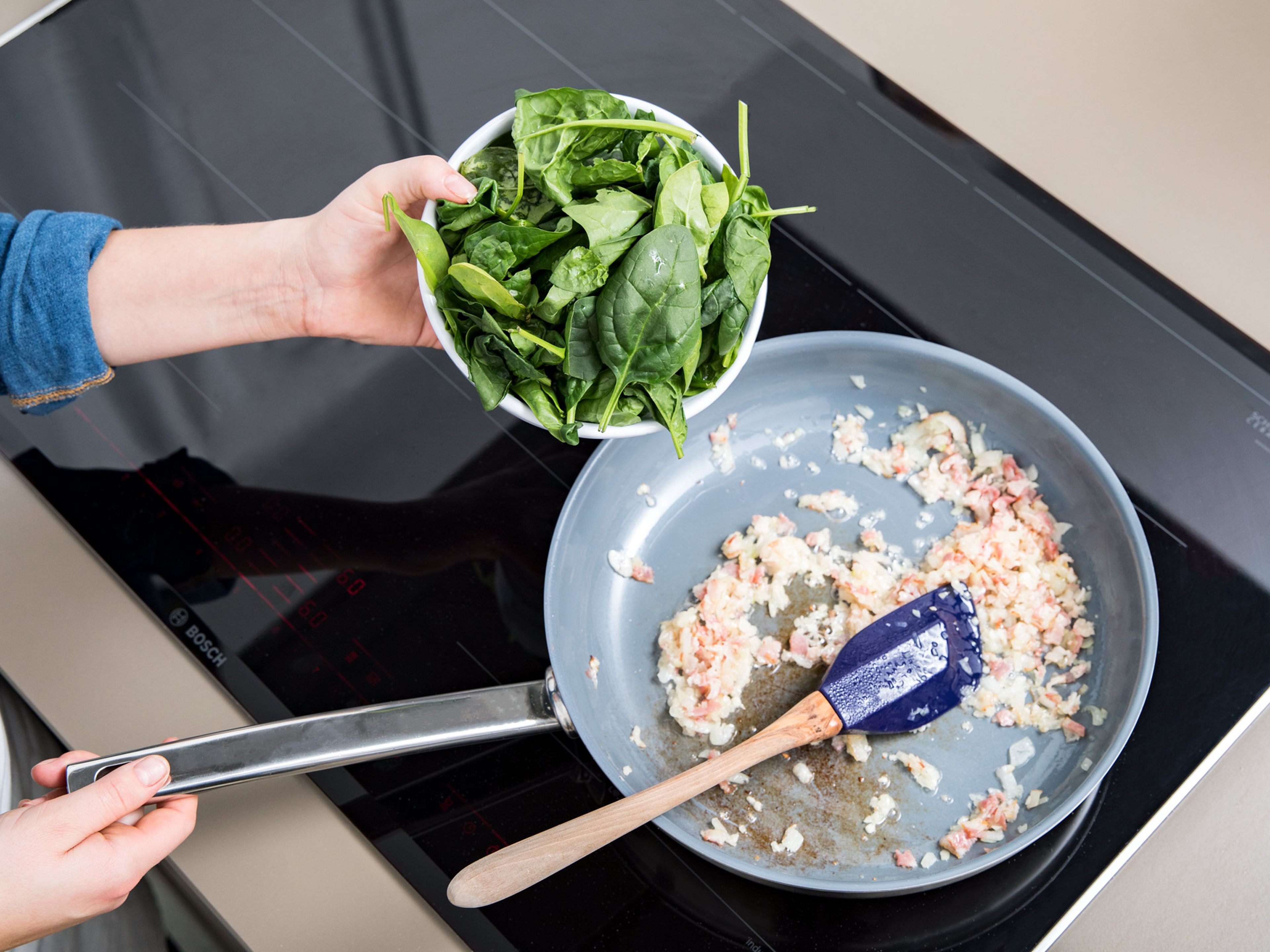 Heat sunflower oil in a large frying pan. Add onion, bacon, and garlic. Once onion is translucent, add spinach, season with nutmeg, and sauté until spinach is wilted.
