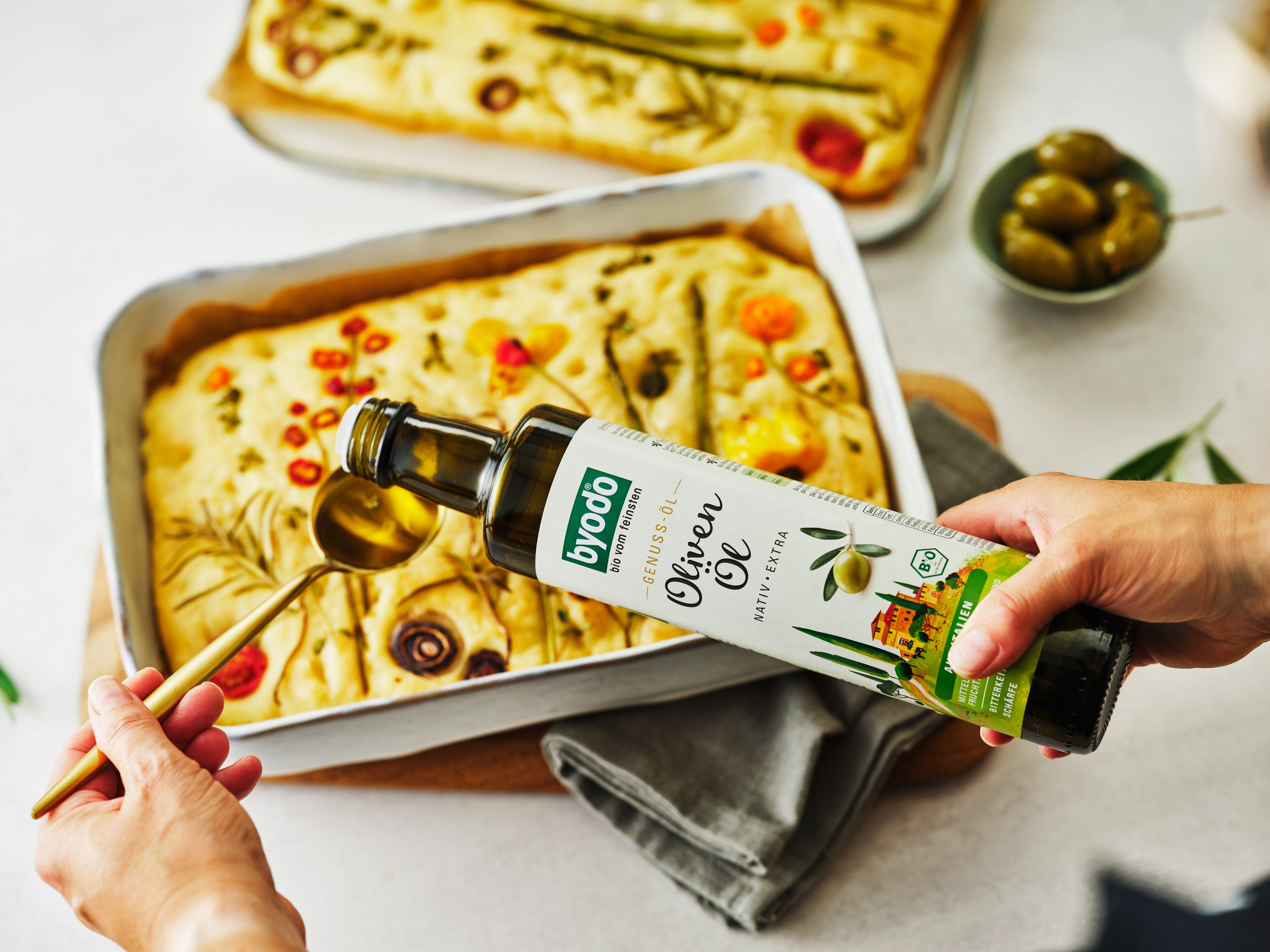 Die Focaccia aus dem Ofen nehmen und kurz auf einem Gitter etwas abkühlen lassen. Dann mit Italienischem Olivenöl beträufeln und frisch servieren.
