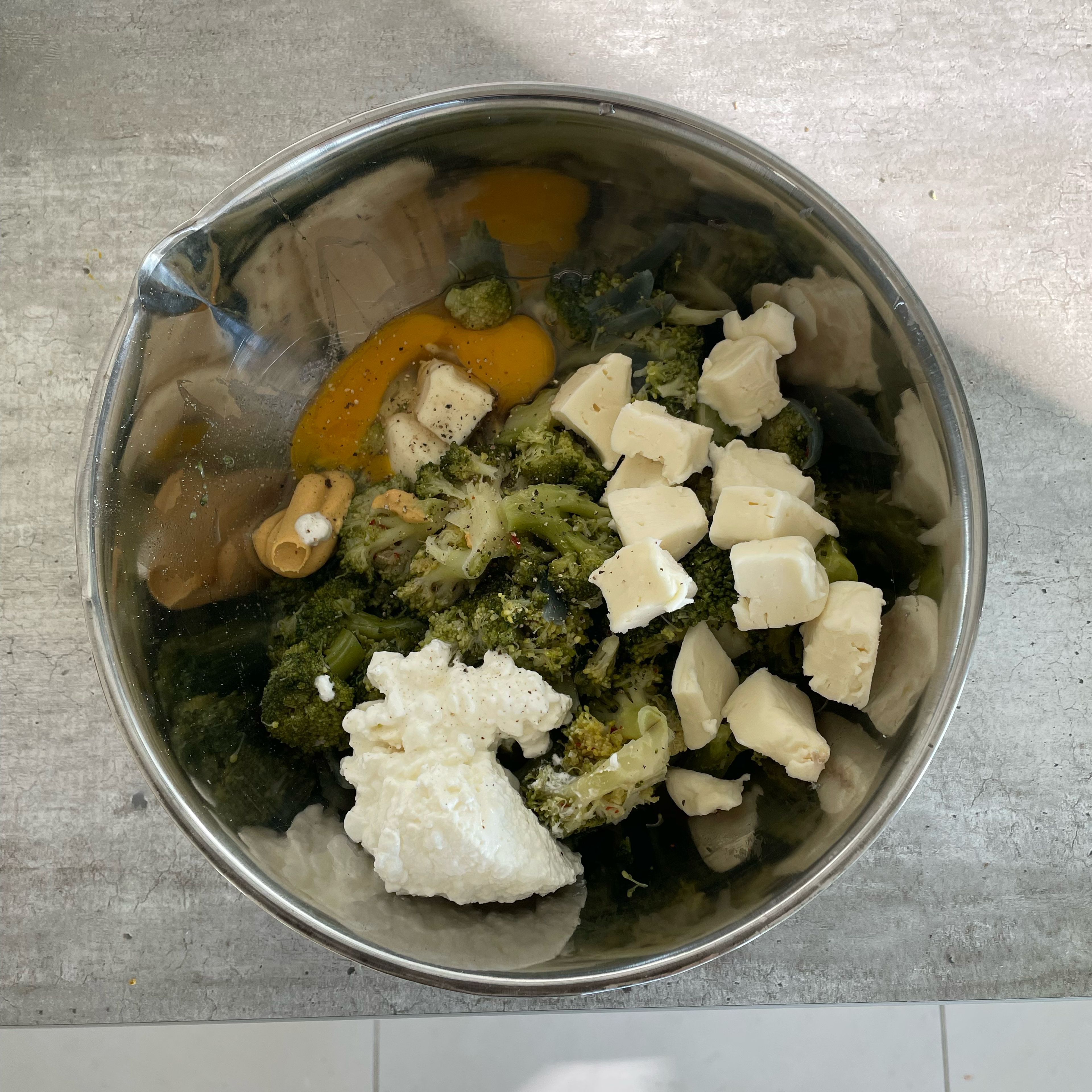 Add the cooked broccoli, egg, mustard, sliced taleggio cheese and cottage cheese to a bowl and mix all ingredients. You can add another pinch of salt and pepper if you like.