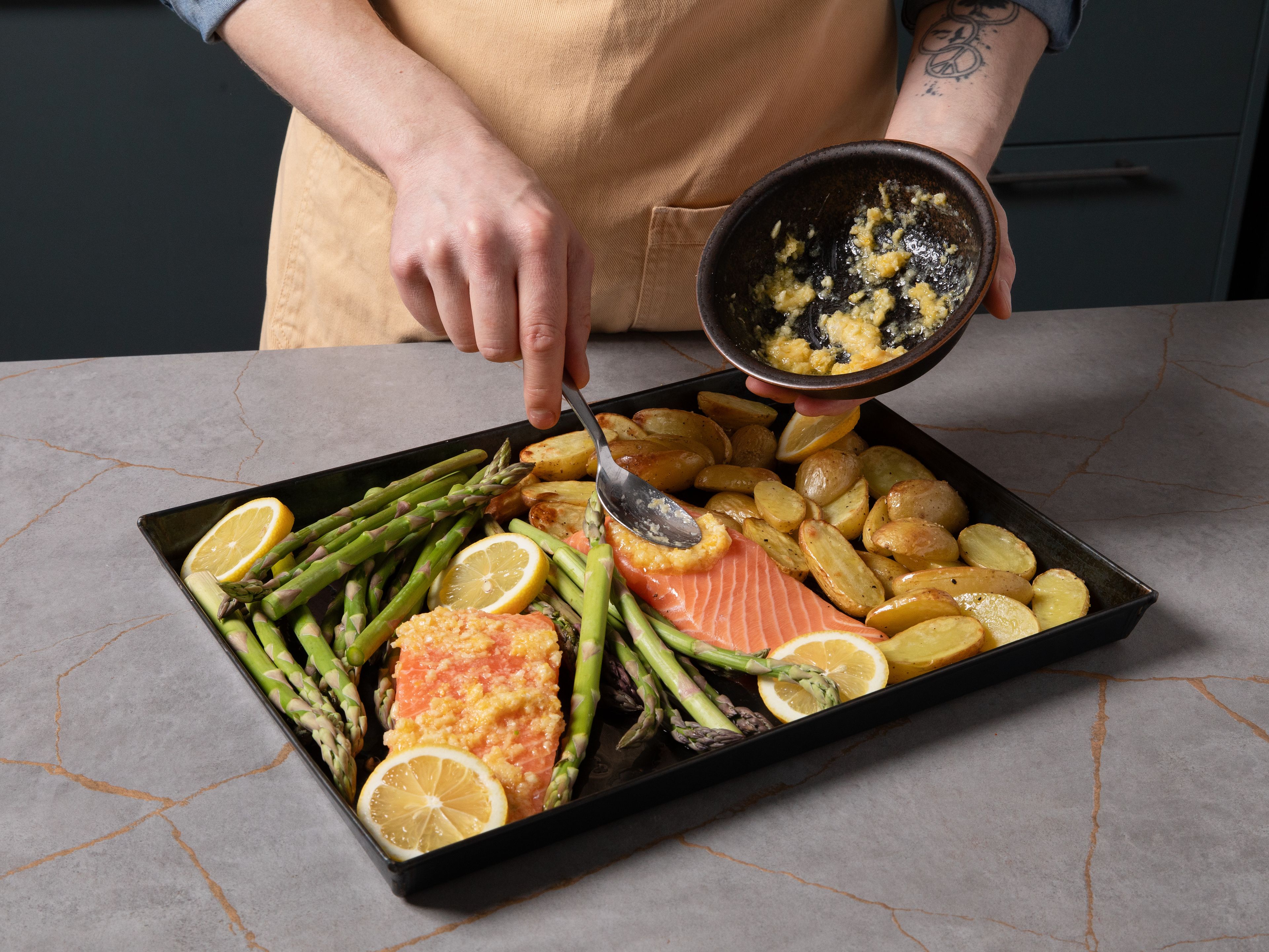 Add the salmon fillets, lemon slices, and green asparagus to the baking sheet. Spread the butter mixture over the salmon, drizzle some oil over the asparagus, and bake for an additional approx. 15–20 min., until the salmon is cooked through, the asparagus is tender, and the potatoes are golden brown. To serve, sprinkle with the remaining Parmesan and garnish with dill.