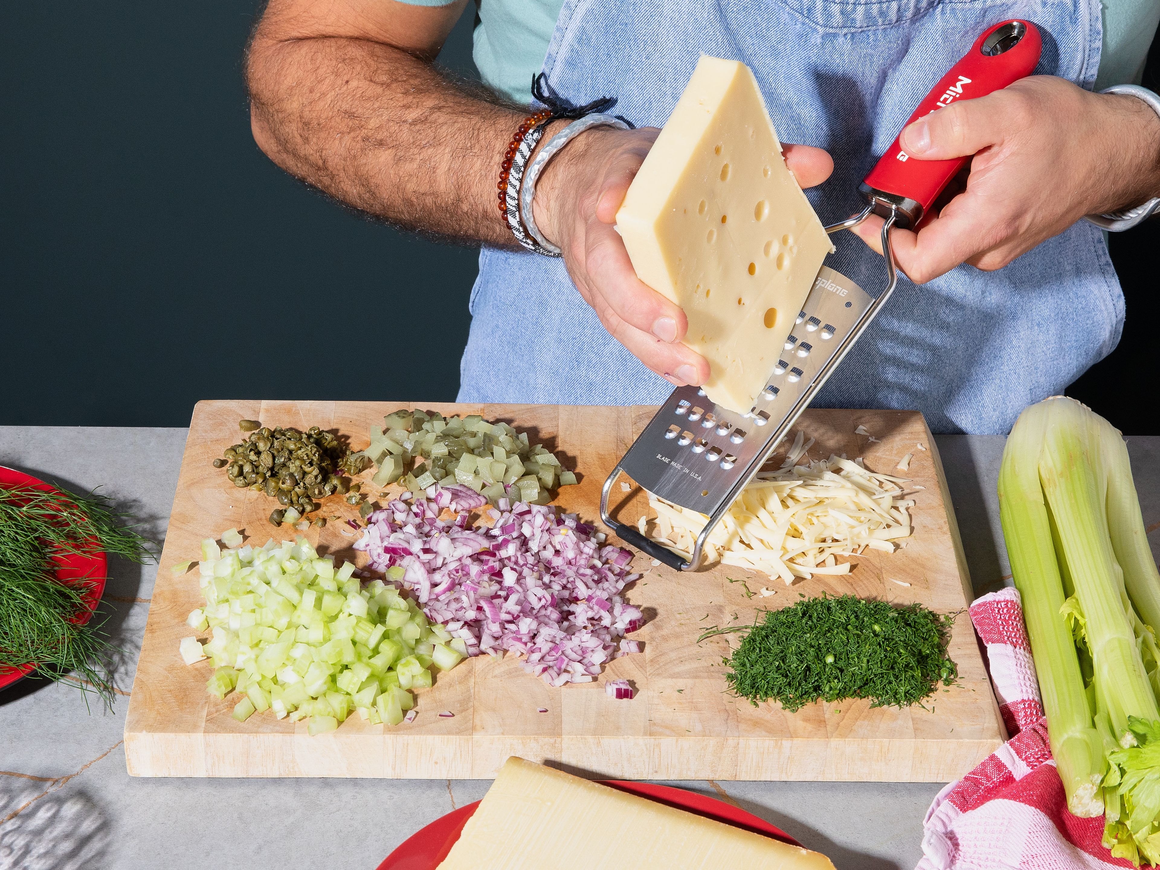 Finely dice onion and celery stalk. Roughly chop capers and pickled cucumbers. Slice dill. Roughly grate the cheeses.