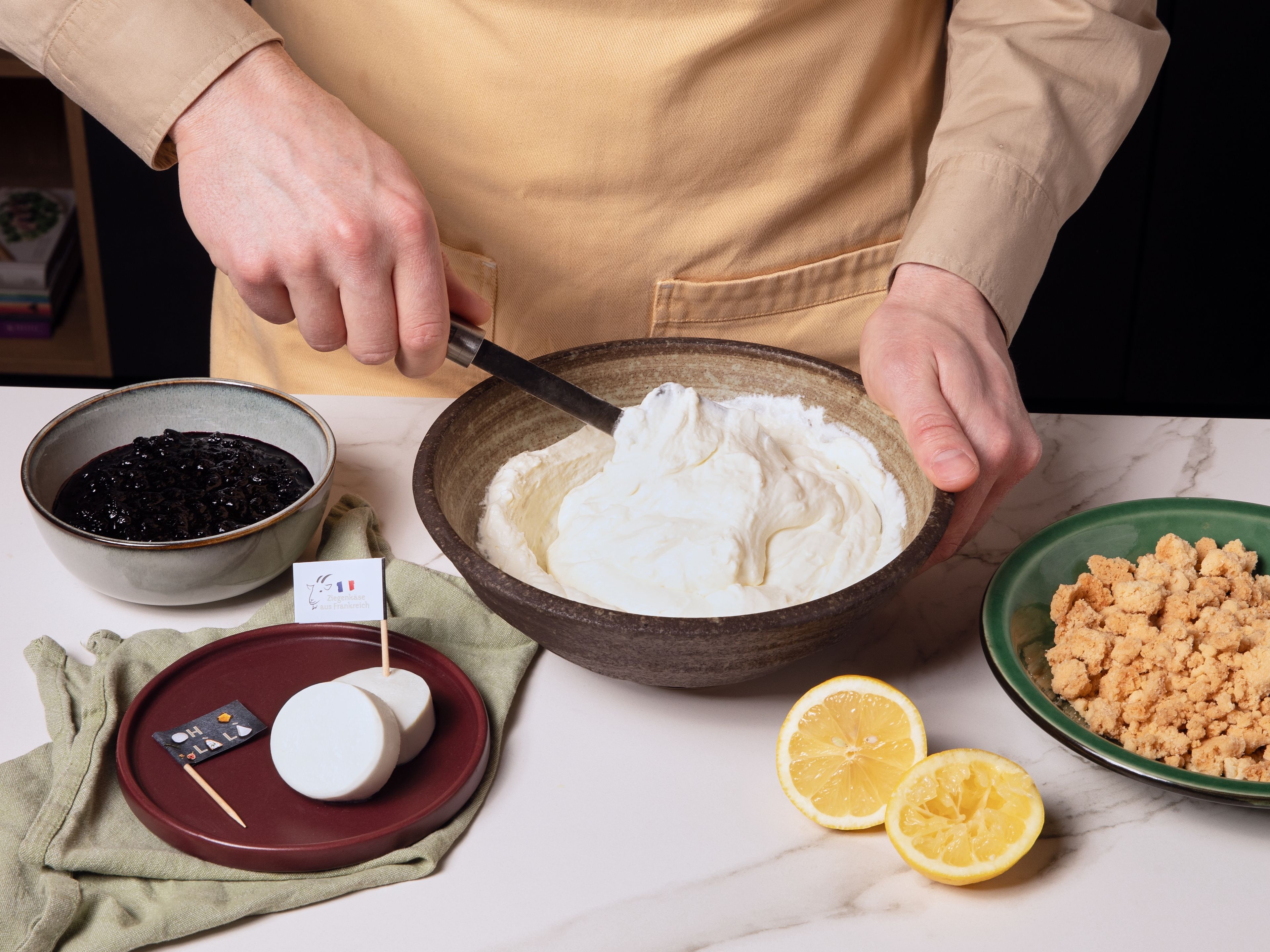 Für die Ziegenkäse-Mousse die herrlich frischen Ziegenkäsetaler aus Frankreich mit Puderzucker und Saft der zweiten Zitronenhälfte glattrühren. Die Schlagsahne steif schlagen und vorsichtig unter die Käsemasse heben. Die Mousse für mindestens ca. 30 Min. im Kühlschrank ruhen lassen. Zum Anrichten die Ziegenkäse-Mousse mit einem Löffel oder Spritzbeutel auf Tellern oder in Gläsern verteilen. Das abgekühlte Blaubeerkompott darübergeben und mit dem knusprigen Zitronen-Crumble bestreuen. Sofort servieren und genießen!