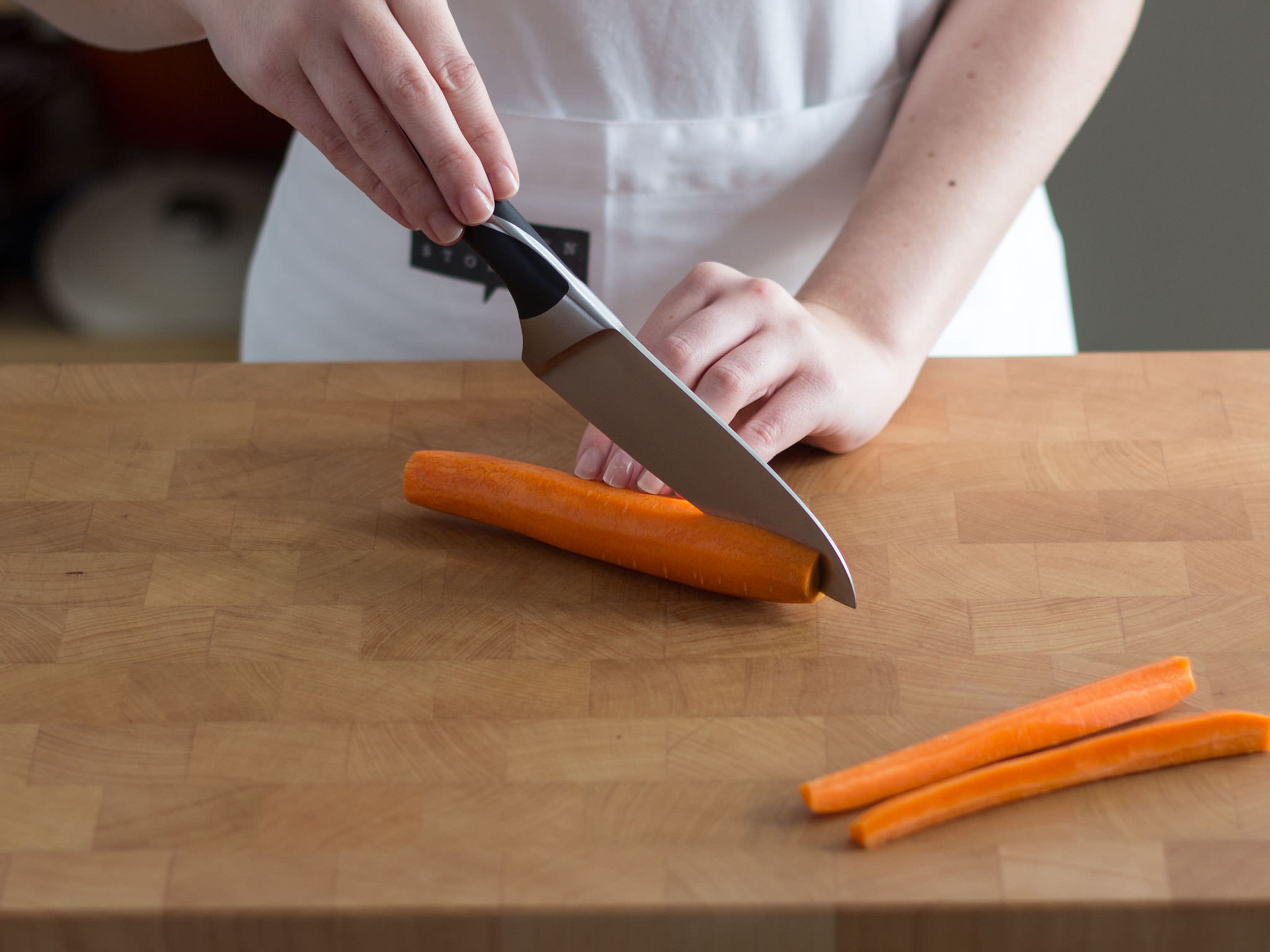Backofen auf 180°C vorheizen. Haut des Schinkens rauten- bzw. gitterförmig einschneiden. Karotten schälen und der Länge nach vierteln.