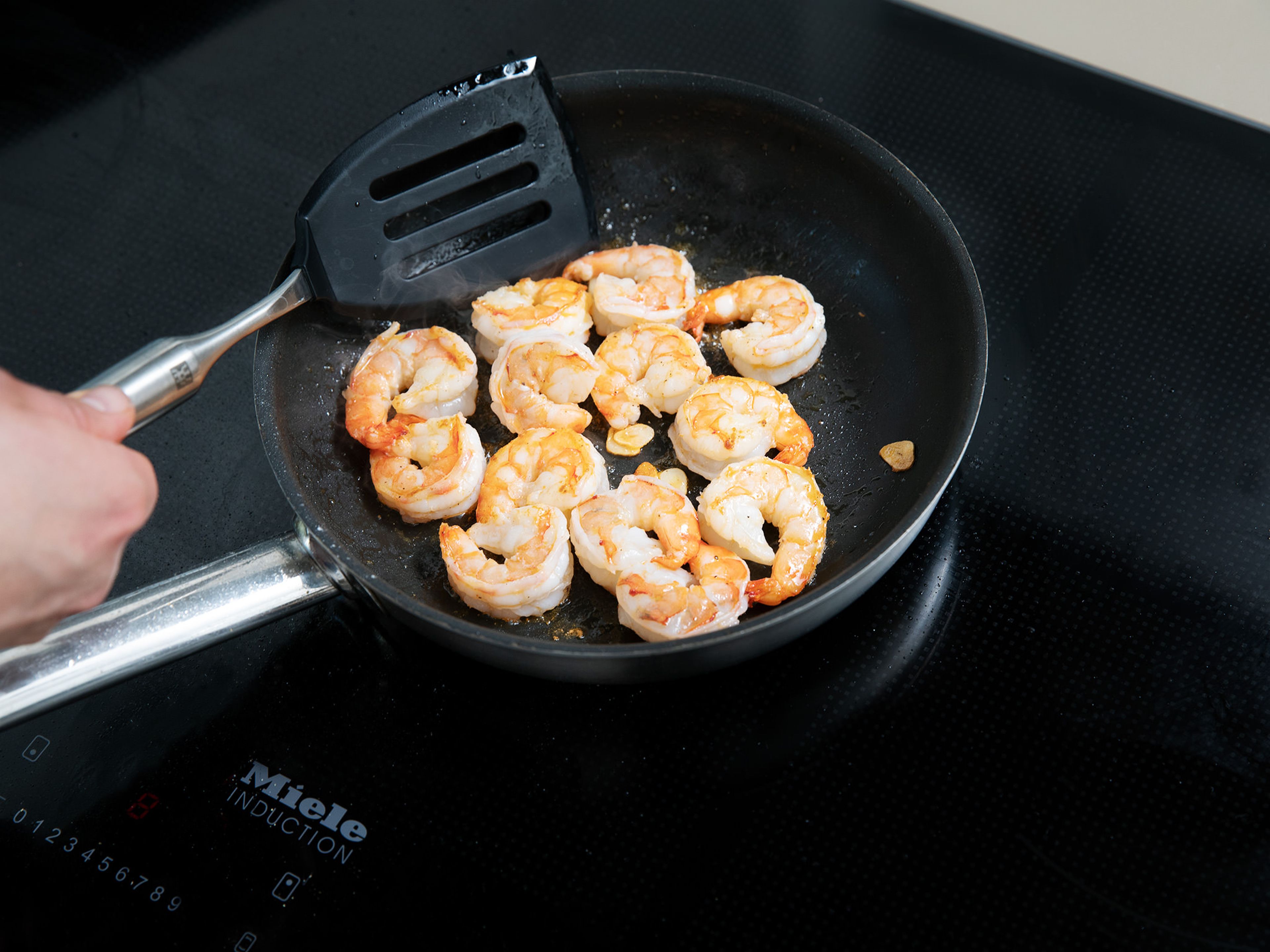 In a second frying pan, heat some toasted sesame oil and fry shrimp on medium-high heat for approx. 3 min. or until cooked through. Season with salt and pepper and toss in sweet chili sauce.