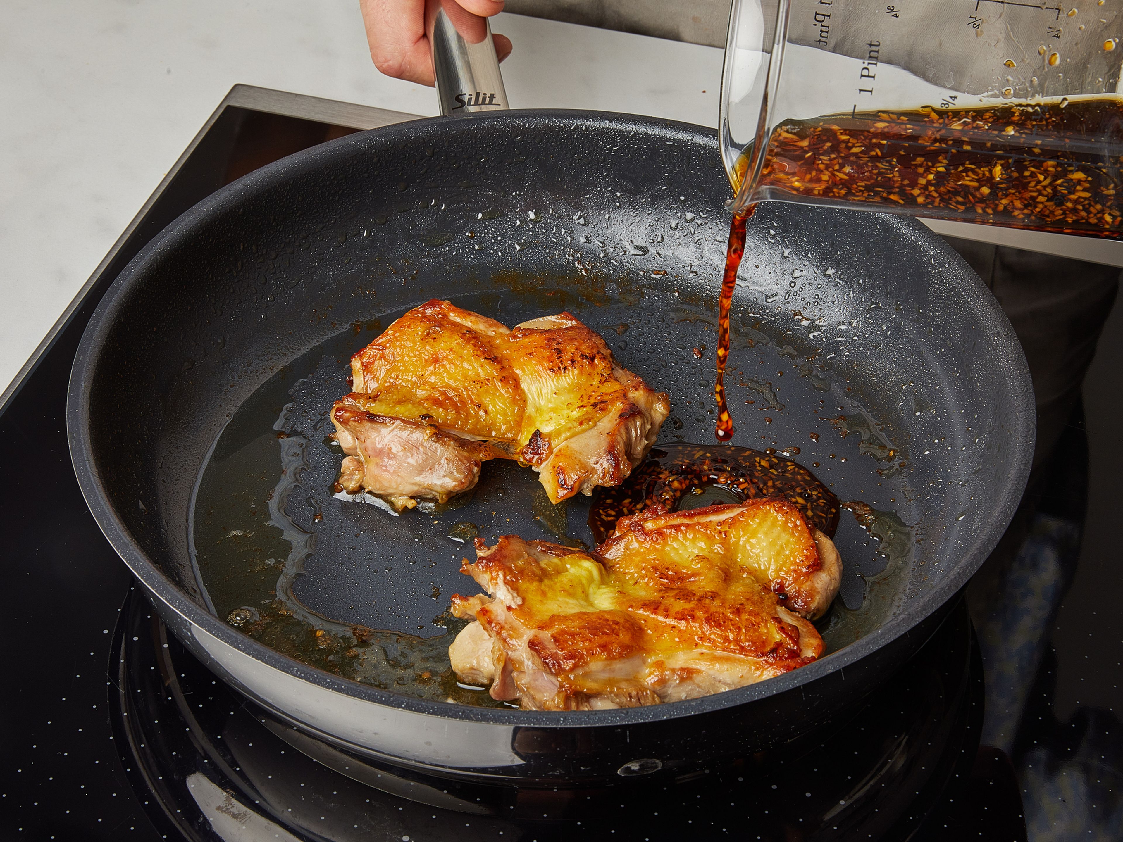 In a frying pan, heat vegetable oil over medium heat, add chicken thighs skin-side down and fry until the skin is golden brown, flip and fry the other side until golden and chicken is cooked through, about 4-6 minutes per side. Lower the heat, flip the chicken thighs so the skin side is facing up, add the teriyaki sauce, let simmer until small bubbles form and the sauce is reduced and becomes syrupy, for about 3 min. Remove from the pan, and reserve the sauce.