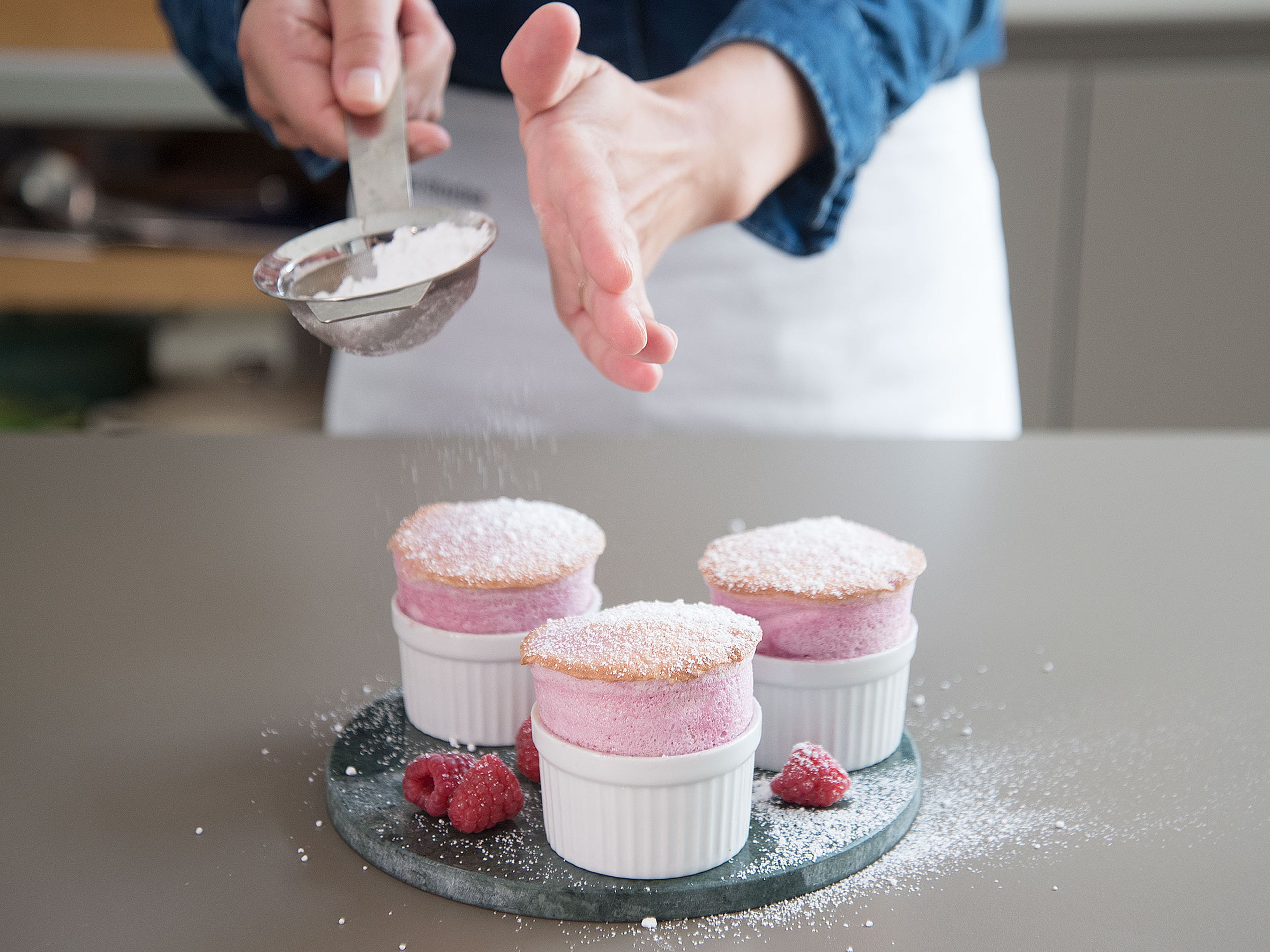 Serve the soufflés warm with powdered sugar and fresh raspberries. Enjoy!