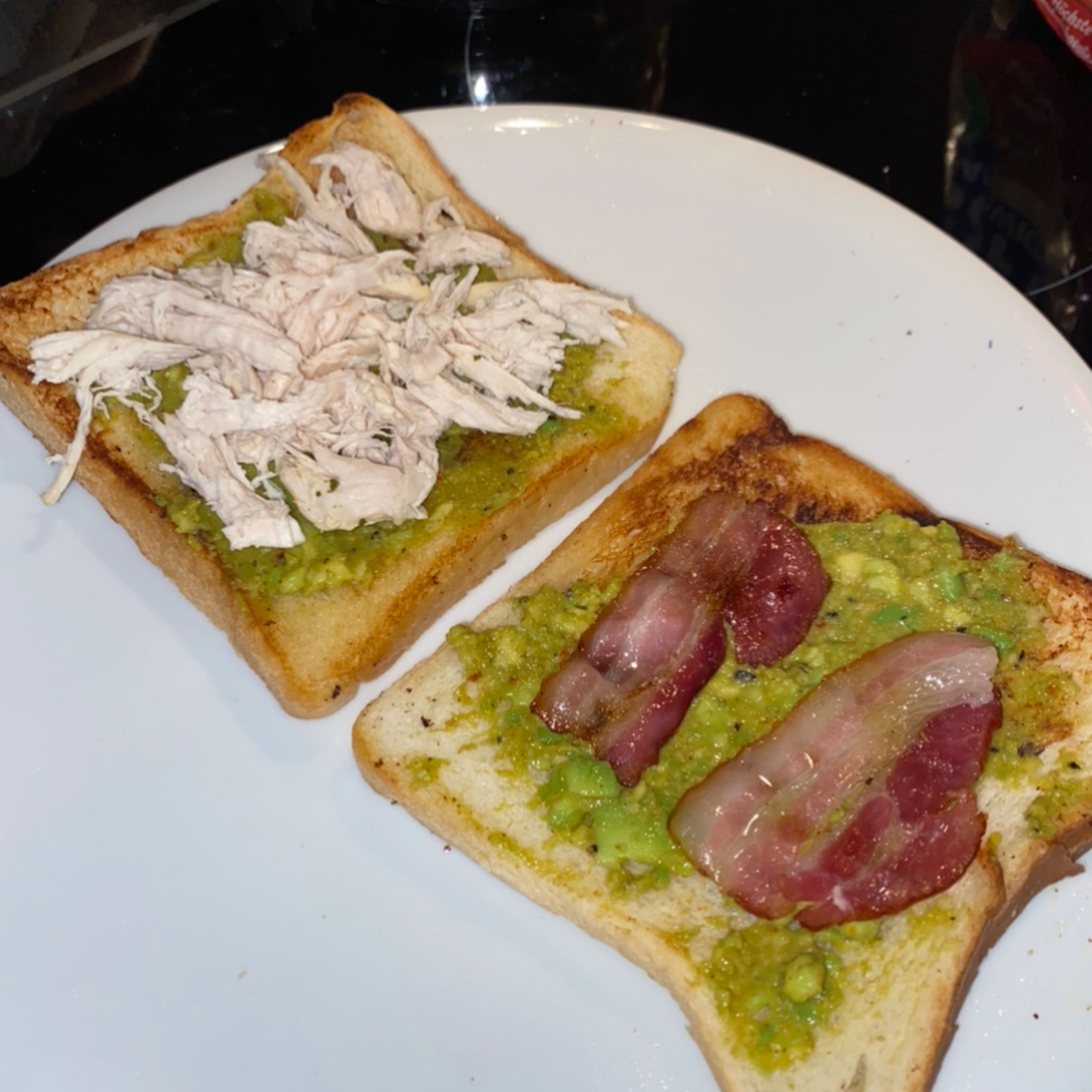 Nun werden die Brötchen belegt. Zuerst Guacamole auf zwei Toast verstreichen. Auf der einen Seite das Pulled-Chicken verteilen, auf der anderen den Speck.