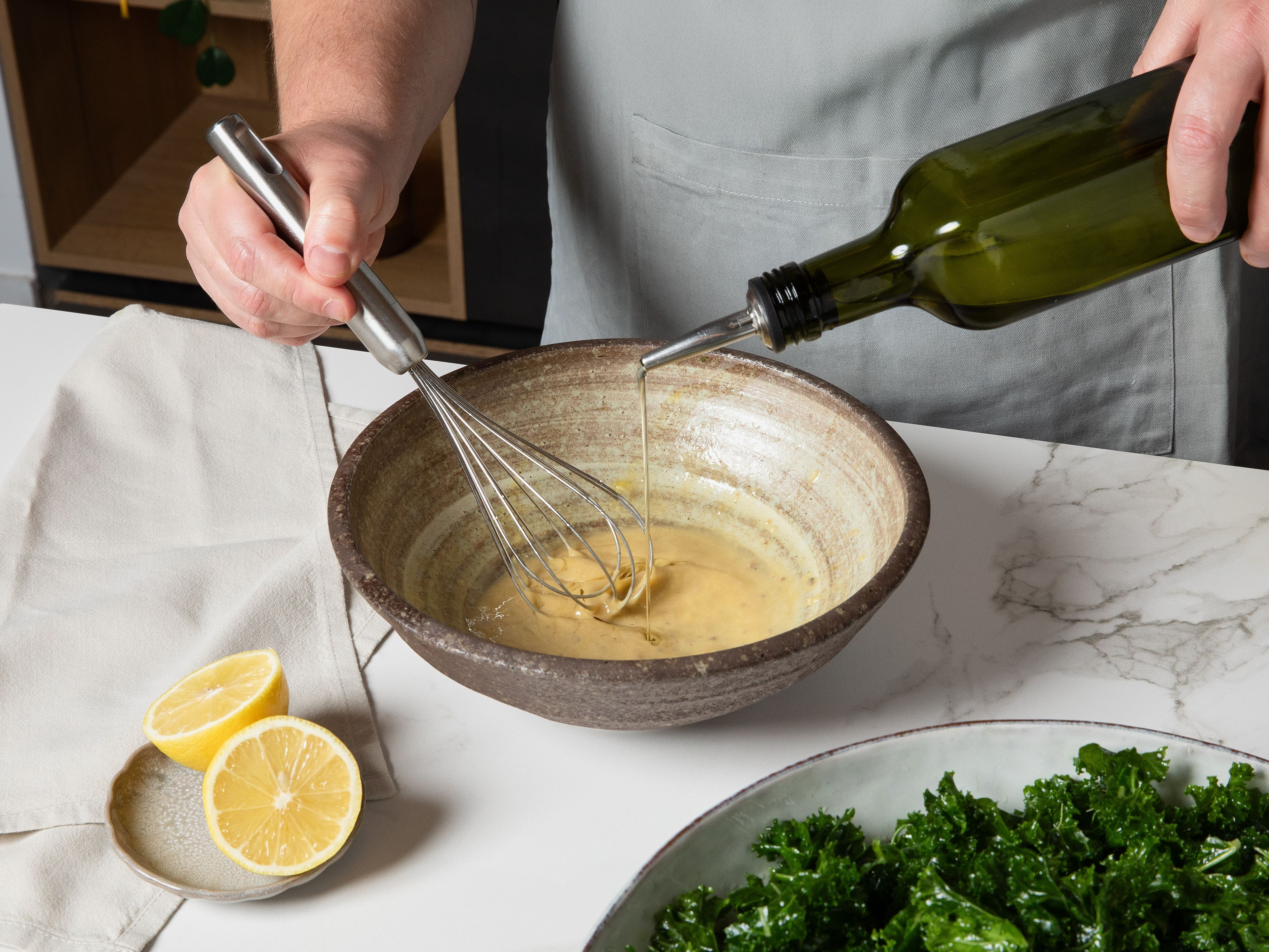Für das Dressing Eigelb, Senf, Worcestersauce, und (falls gewünscht) Sardellen in einer Schüssel verrühren. Knoblauch hineinpressen und Zitronensaft zugeben und dann langsam das restliche Olivenöl einrühren, bis das Dressing cremig wird. Den Parmesan fein reiben und unter das Dressing rühren, mit Salz und Pfeffer abschmecken. Dressing zum Grünkohl geben, vermengen und kurz ziehen lassen.