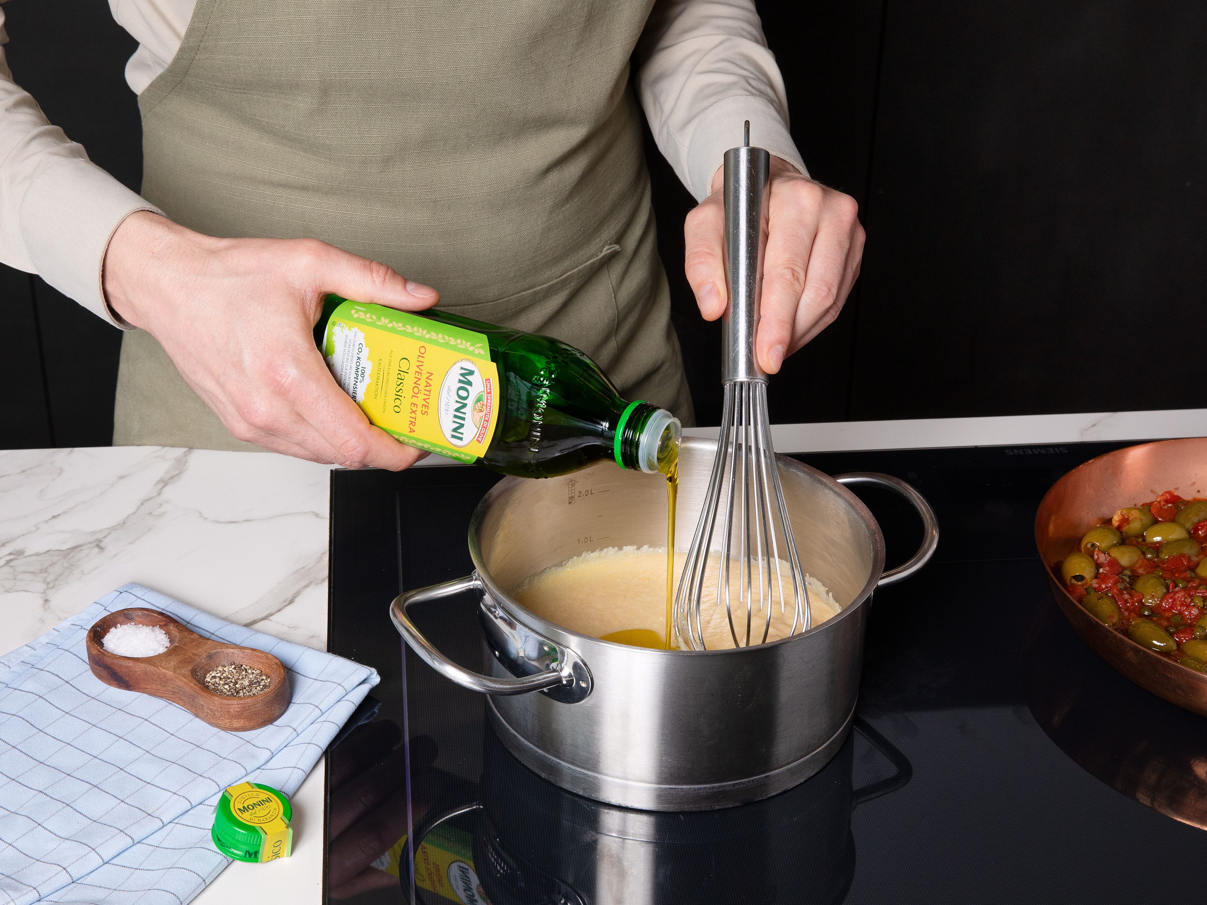 Während der Fisch gart, die Gemüsebrühe in einem Topf aufkochen. Die Polenta langsam einrieseln lassen und unter ständigem Rühren bei niedriger Hitze etwa 5 Minuten köcheln lassen, bis sie eindickt. Parmesan, Sahne und restliches Olivenöl einrühren, mit Salz und Pfeffer abschmecken und warm halten.