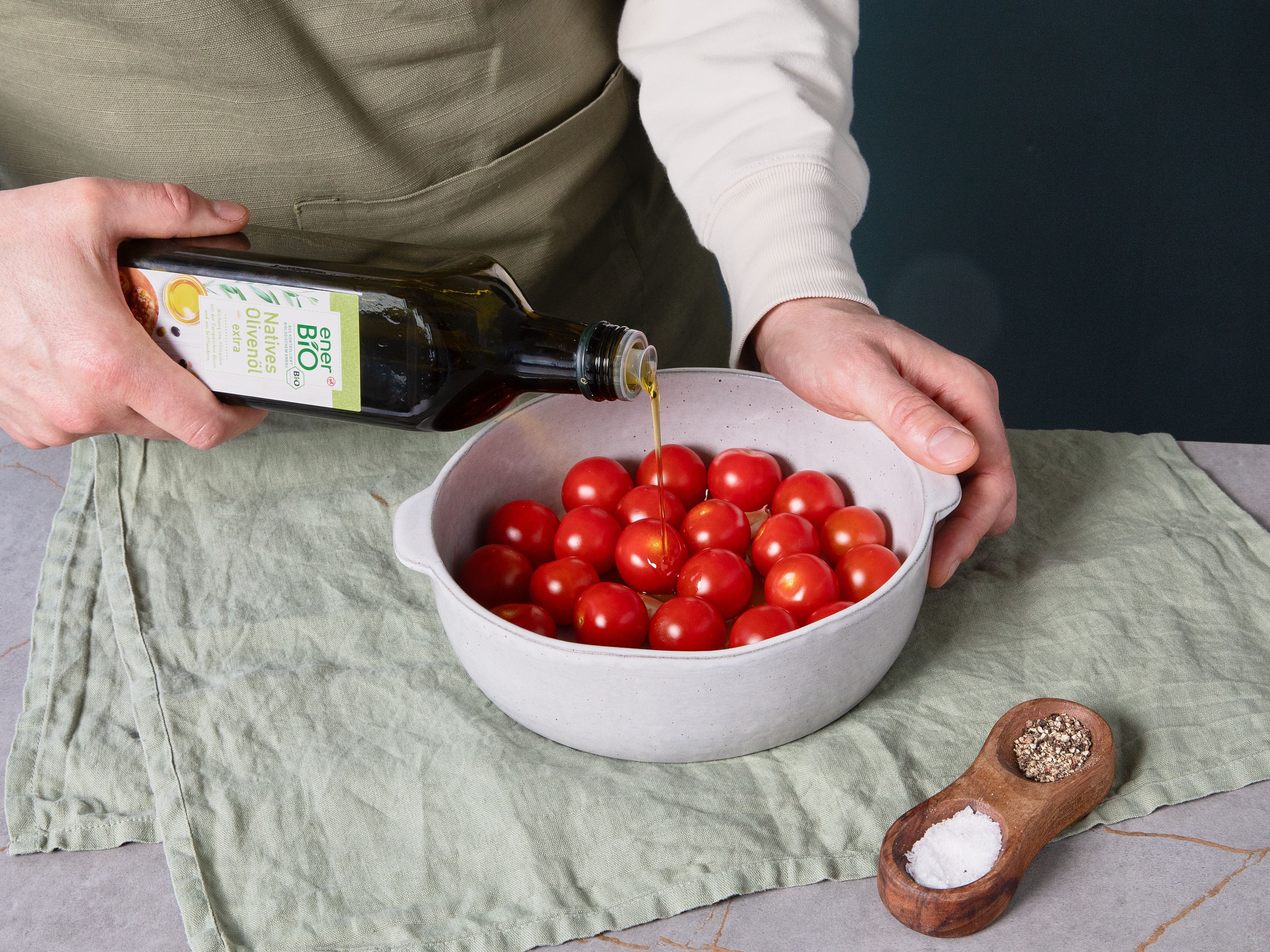 Den Ofen auf 200°C Ober-/Unterhitze vorheizen. Kirschtomaten in eine kleine Ofenform geben. Knoblauchzehen schälen, andrücken und zu den Tomaten geben. Mit etwas enerBiO Natives Olivenöl extra beträufeln, mit Salz und Pfeffer würzen und im Ofen ca. 20–25 Min. backen, bis die Tomaten aufplatzen und weich sind.