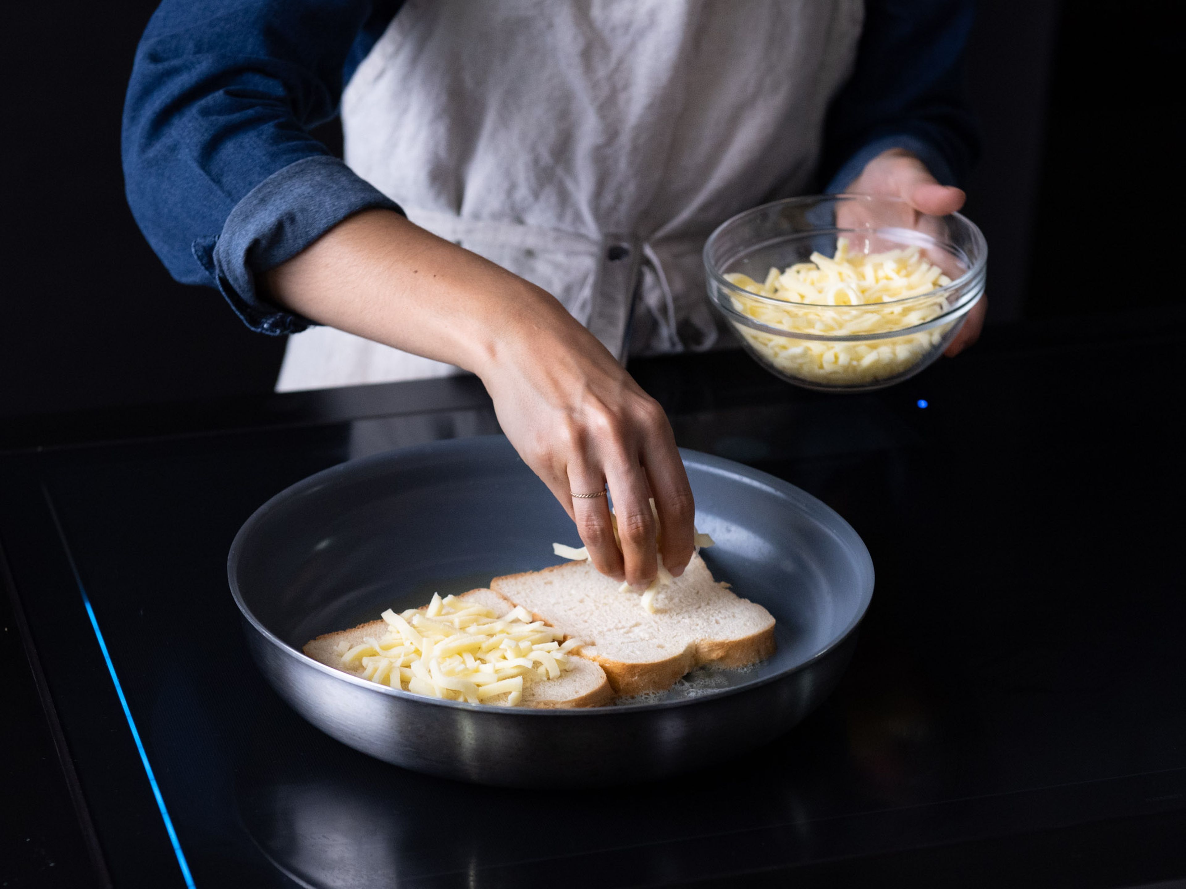 Add some butter and olive oil to a frying pan over medium heat. Once melted, add two slices of bread to the pan and wiggle around a bit to ensure even coverage of the bread in the melted butter and olive oil. Top each slice with a quarter of the shredded mozzarella cheese.