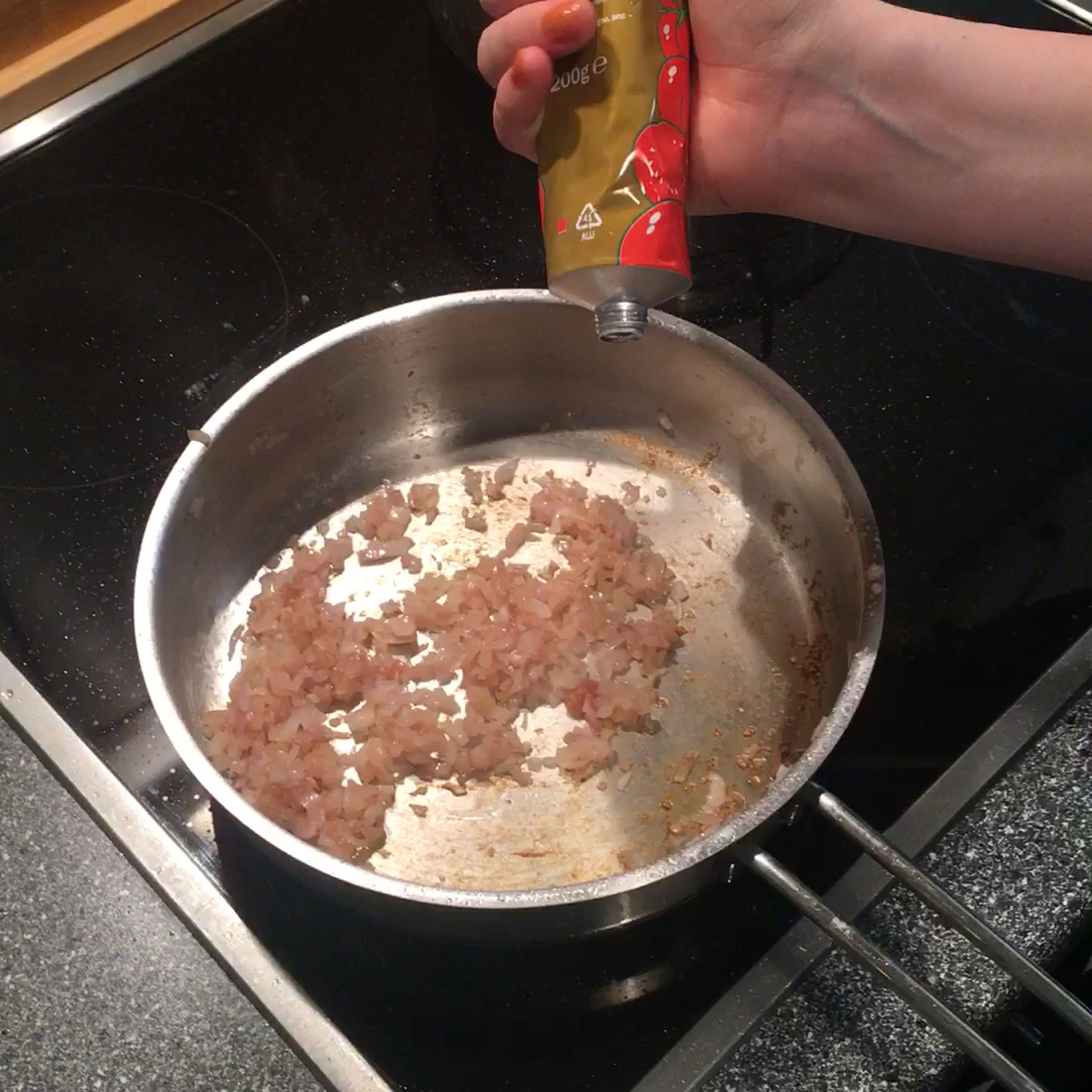 Mixing tomato paste into shallots