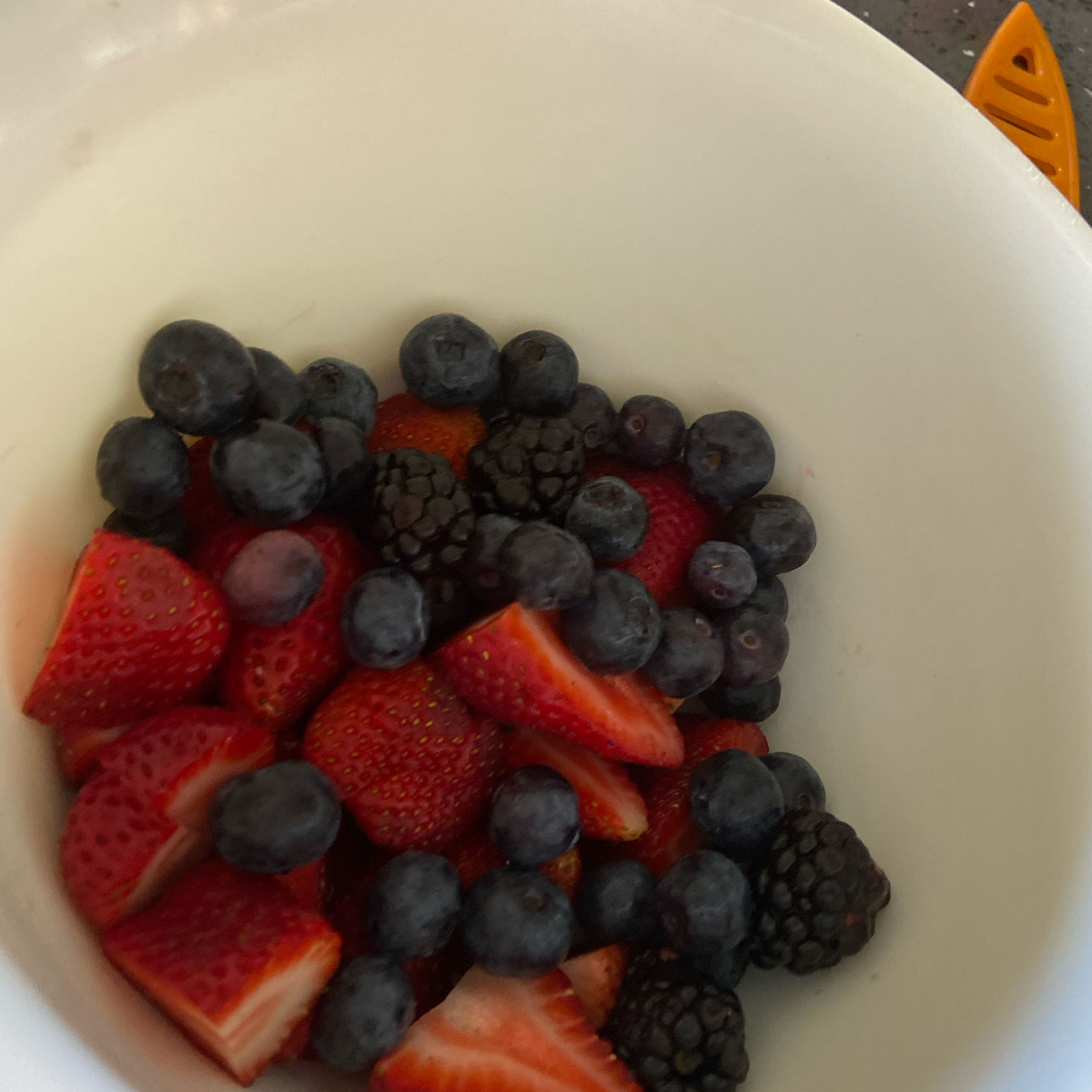 Put a cup of the blueberries and raspberries into the bowl with the strawberries