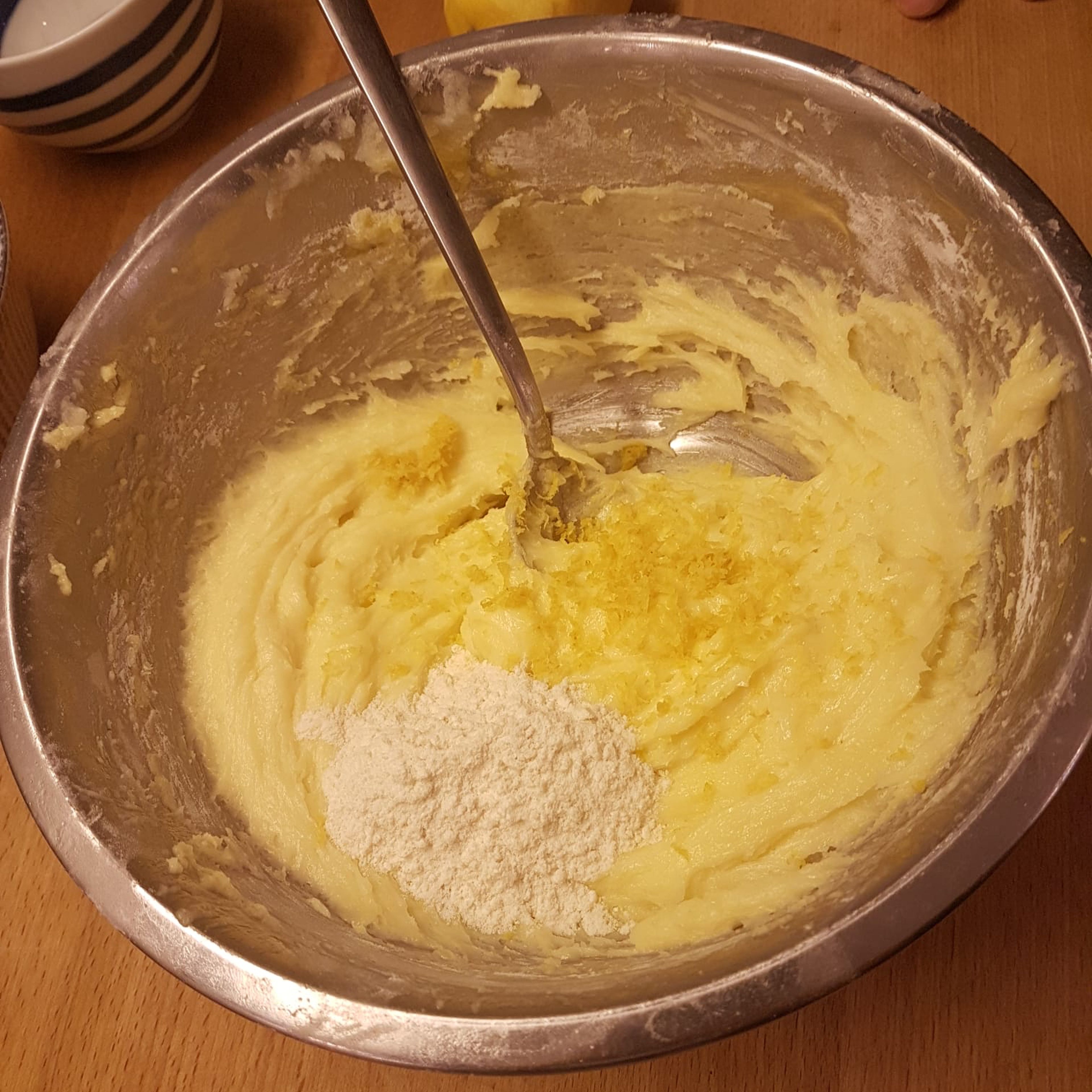 After the starch has been well absorbed, add the grated lemon peel, the baking powder and the spoonful of flour. Mix everything until absorbed