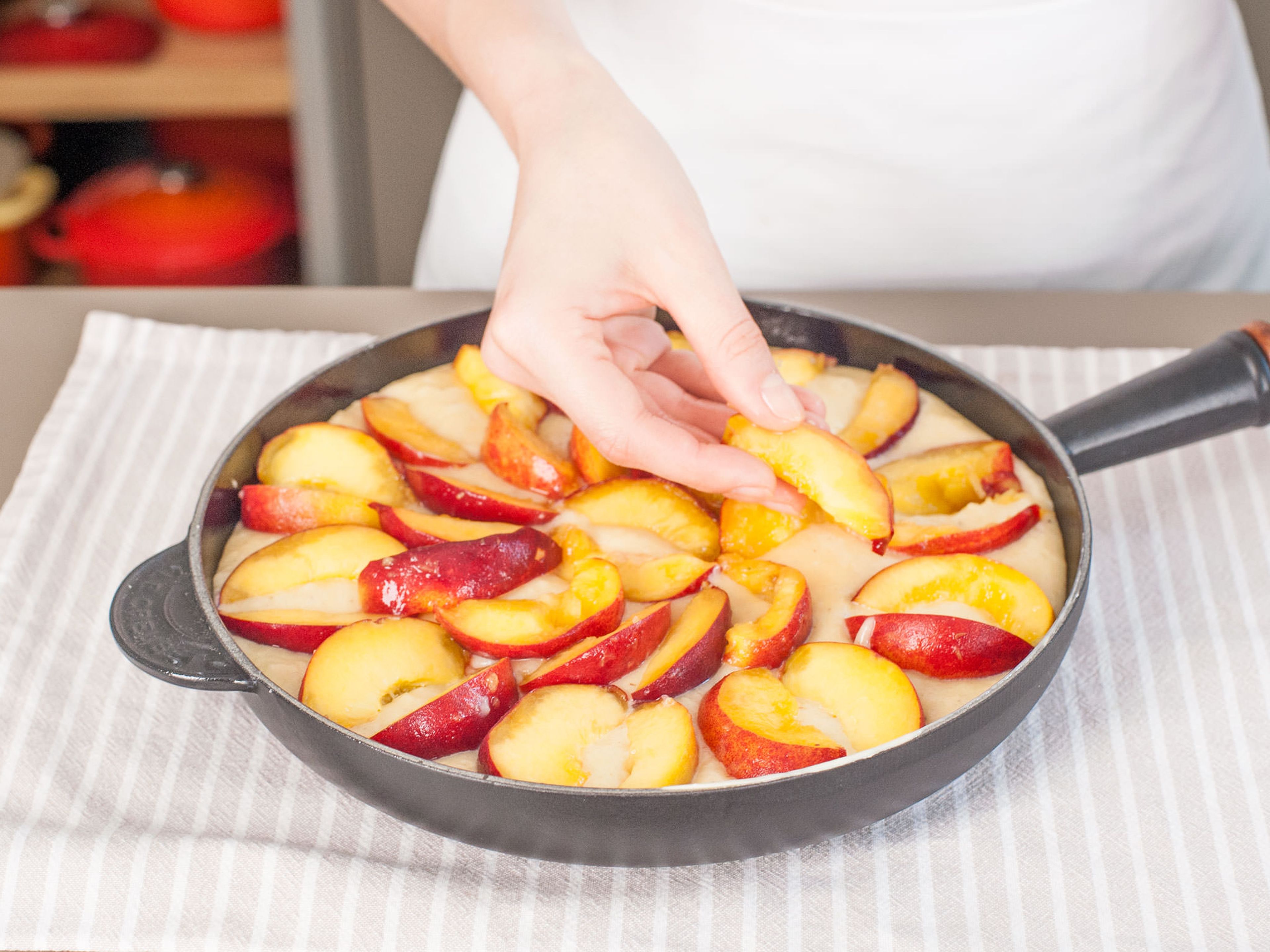 Teig in gusseiserne Pfanne füllen und mit einer Schicht Pfirsichscheiben bedecken.
