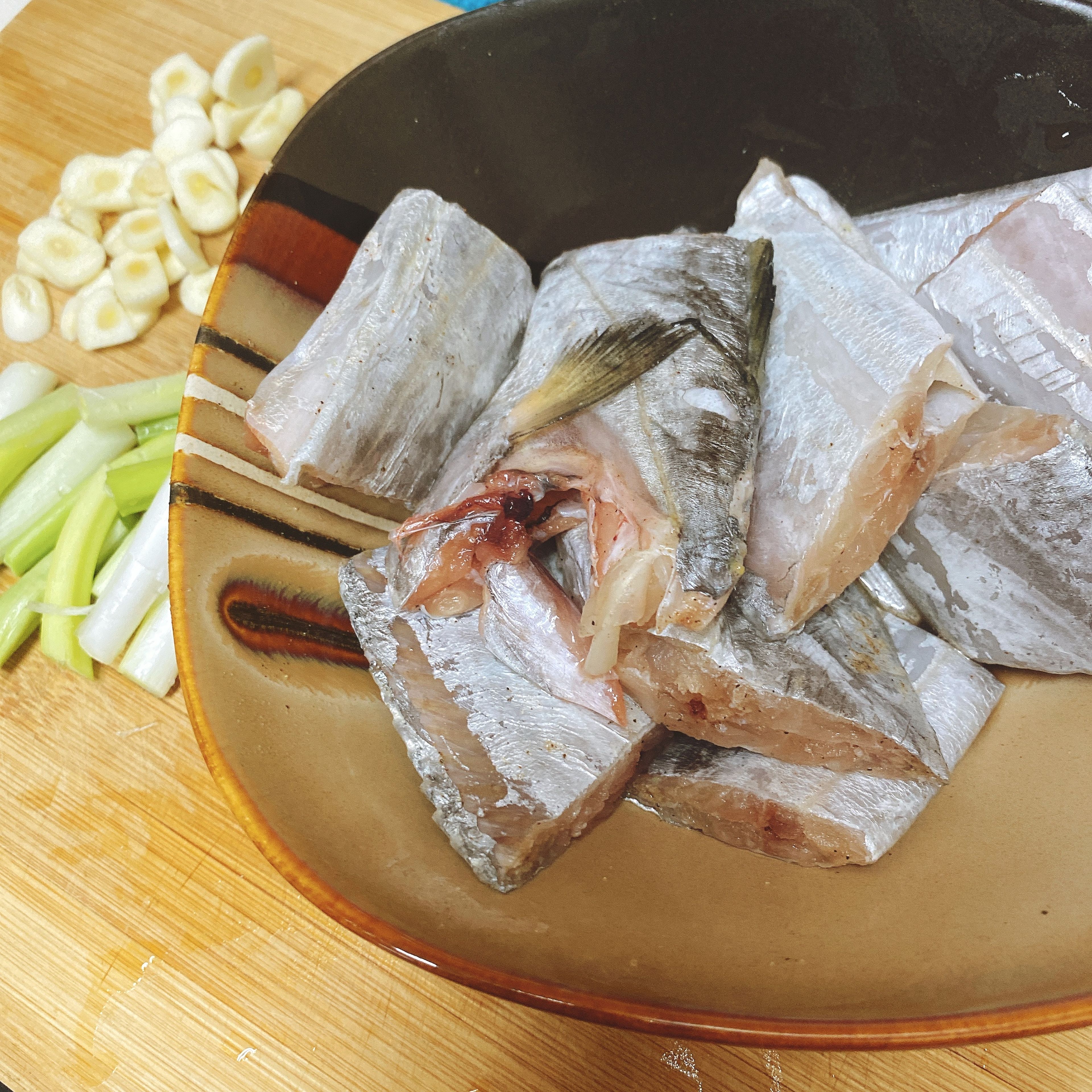 Add the ground white pepper and cooking wine to the gutted fish. While it’s sitting, slice the garlic and chop the scallions