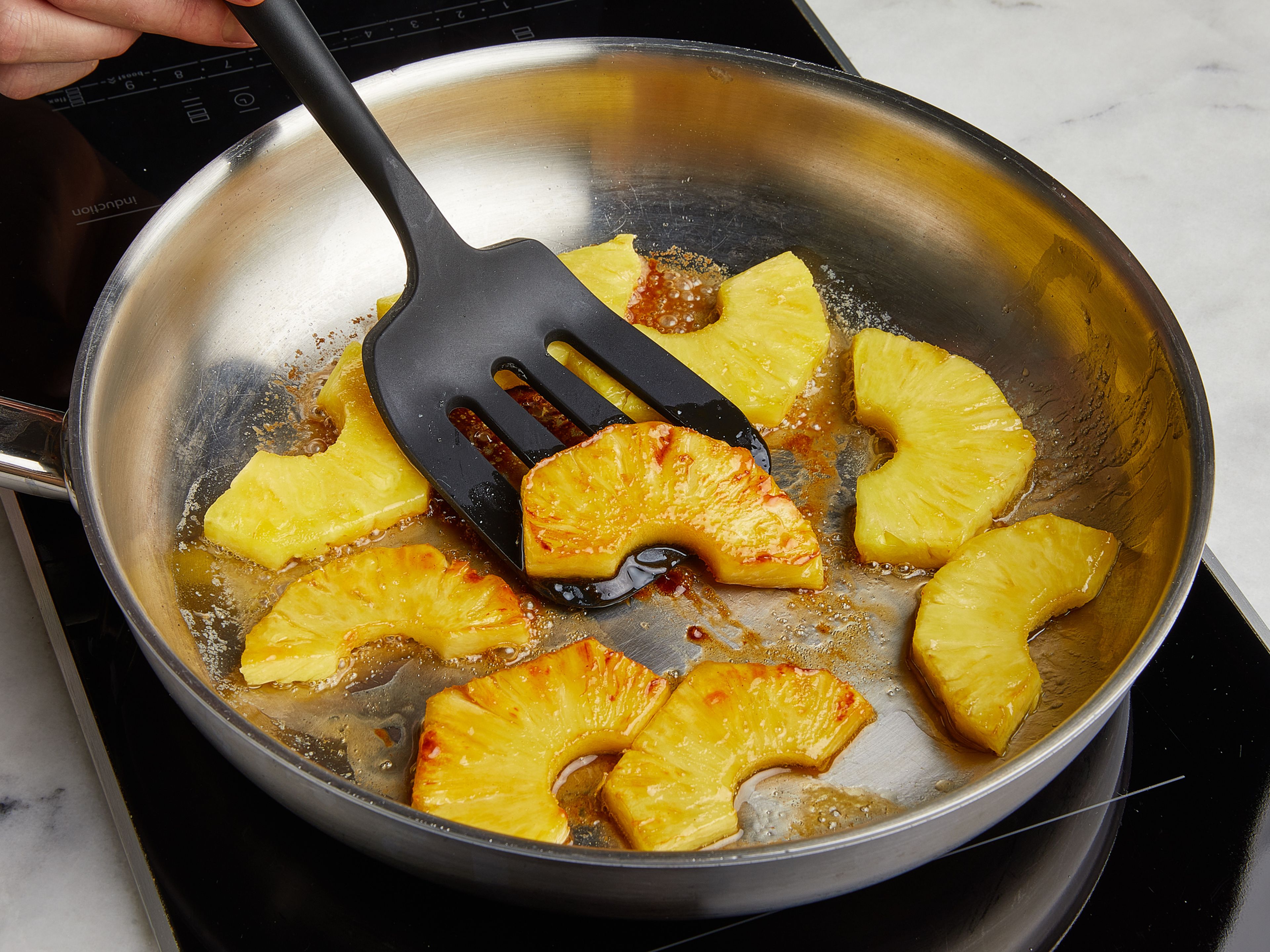 Butter in einer Pfanne bei mittelhoher Stufe zerlassen. Ananasscheiben in die Pfanne geben und von beiden Seiten garen, bis der Zucker karamellisiert. Es darf nicht zu heiß sein, sonst verbrennt die Butter!