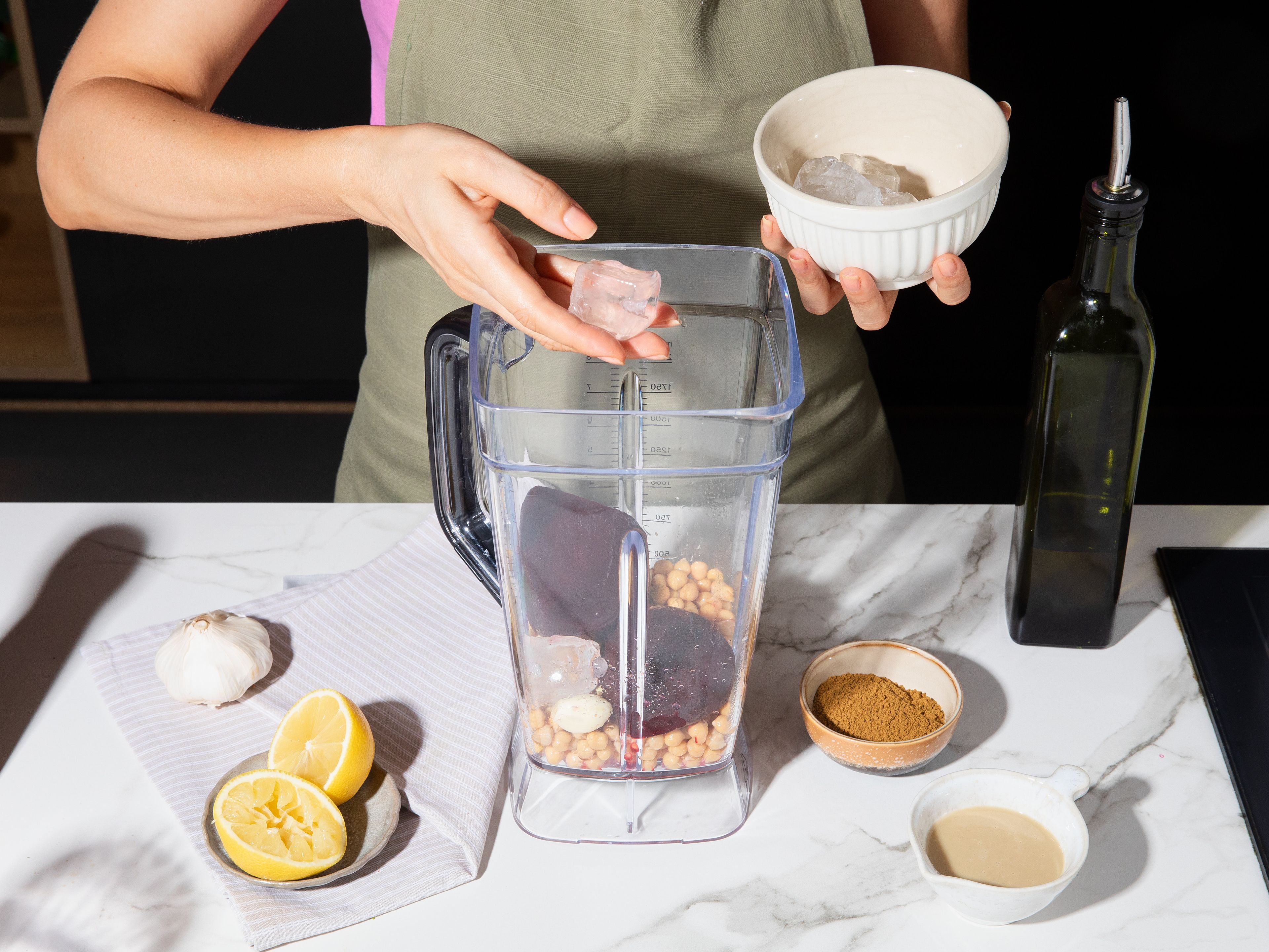 Meanwhile, for hummus, add beetroot, chickpeas, tahini, half of garlic, lemon juice, cumin, and part of olive oil in blender and puree until creamy. During mixing, gradually add 1–2 ice cubes until hummus is particularly creamy and airy. Season with salt and pepper.