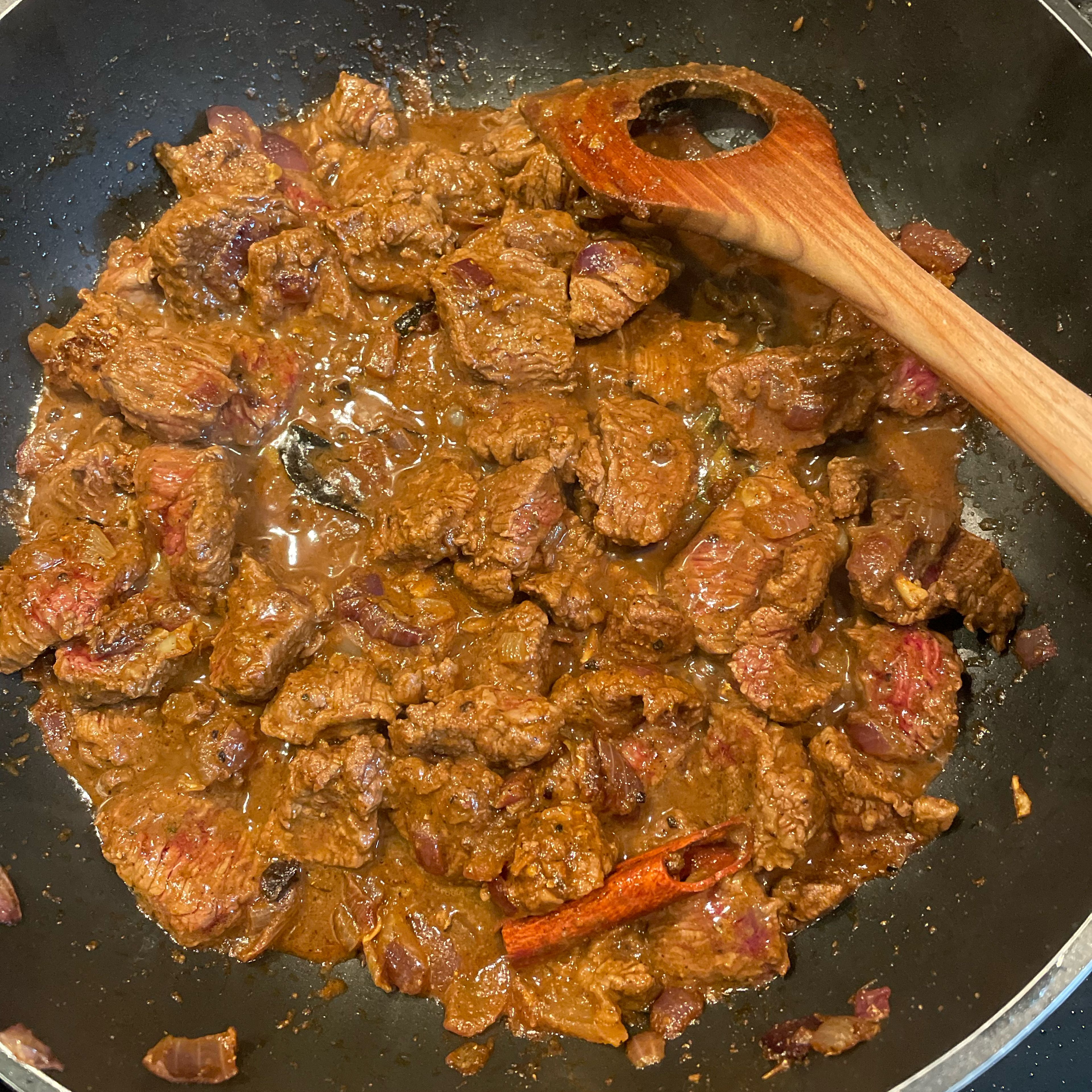 Add beef to the curry base, stir-fry until fully coated and sealed. Then add tamarind juice. Mix with the beef and simmer for 2-3 min on medium heat, then add salt, turmeric and optionally one sliced tomato. Cover and simmer for 20min. Stir occasionally. After 20 min you should have a nice dark base for the curry gravy. While the curry simmers, peel and cube 3 small potatoes.