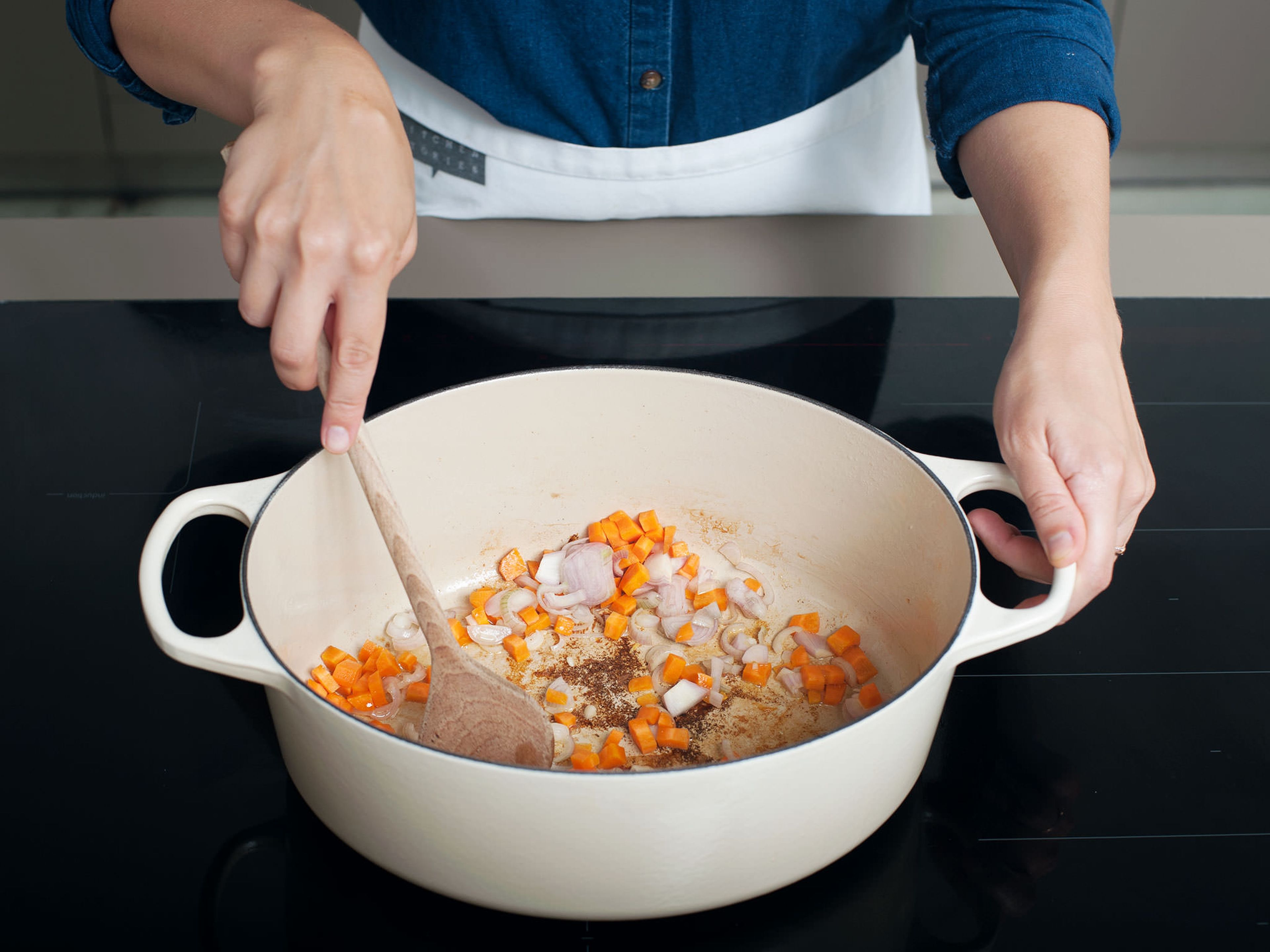 Ofen auf 150°C vorheizen. Vom ausgetretenen Fett fast alles entfernen und nur einen Rest zum Anbraten des Gemüse im Topf lassen. Anschließend Karotten, Knoblauch und Schalotten in den Topf geben. Bei mittlerer Hitze für 3 - 5 min. anschwitzen bis das Gemüse weich wird und anfängt zu duften.