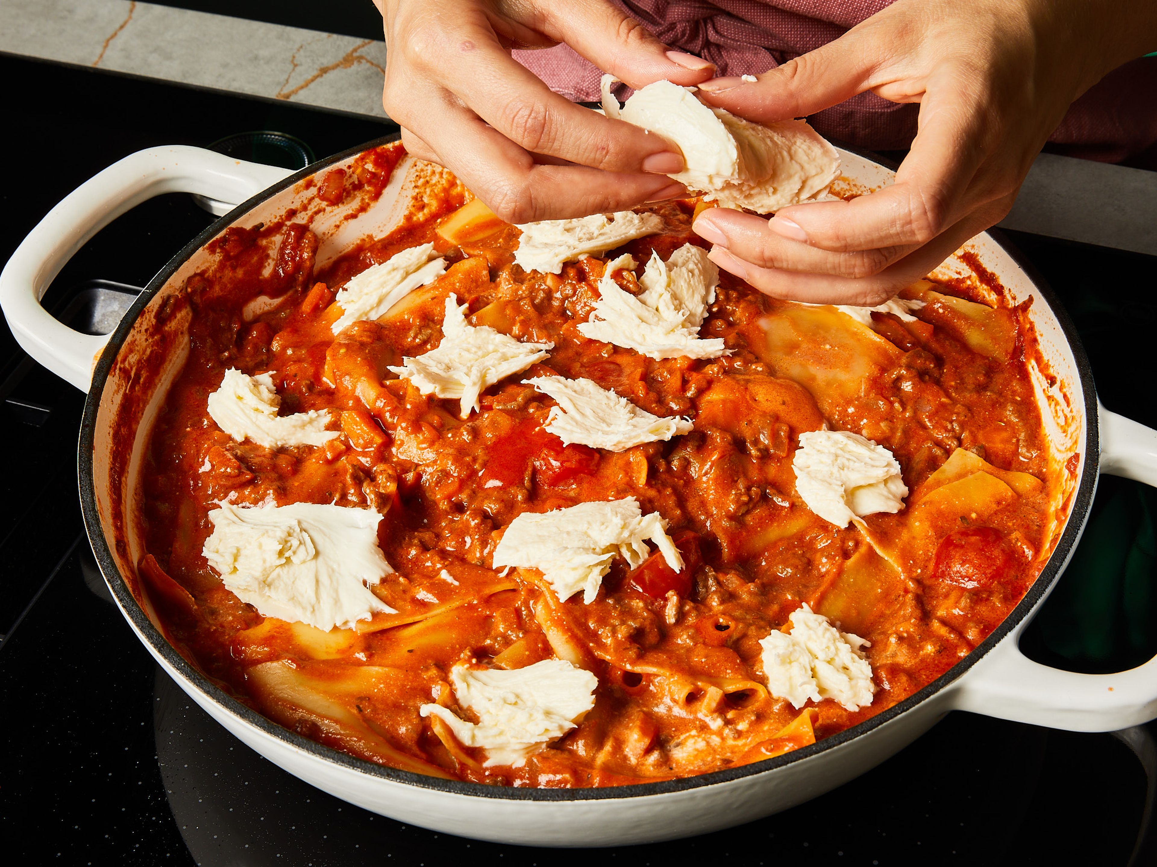 Den Deckel abnehmen und die Mascarpone einrühren. Mozzarella in Stücke zupfen und die Lasagne damit bedecken, den Parmesan darüber reiben. Wenn du eine ofenfeste Pfanne verwendest, bei 230°C Ober-/Unterhitze für ca. 10 Min. im Ofen überbacken, bis der Käse gebräunt und knusprig ist. Alternativ für ca. 10 Min. zugedeckt auf dem Herd stehen lassen, bis der Käse geschmolzen ist. Mit frischem Basilikum garnieren und servieren.