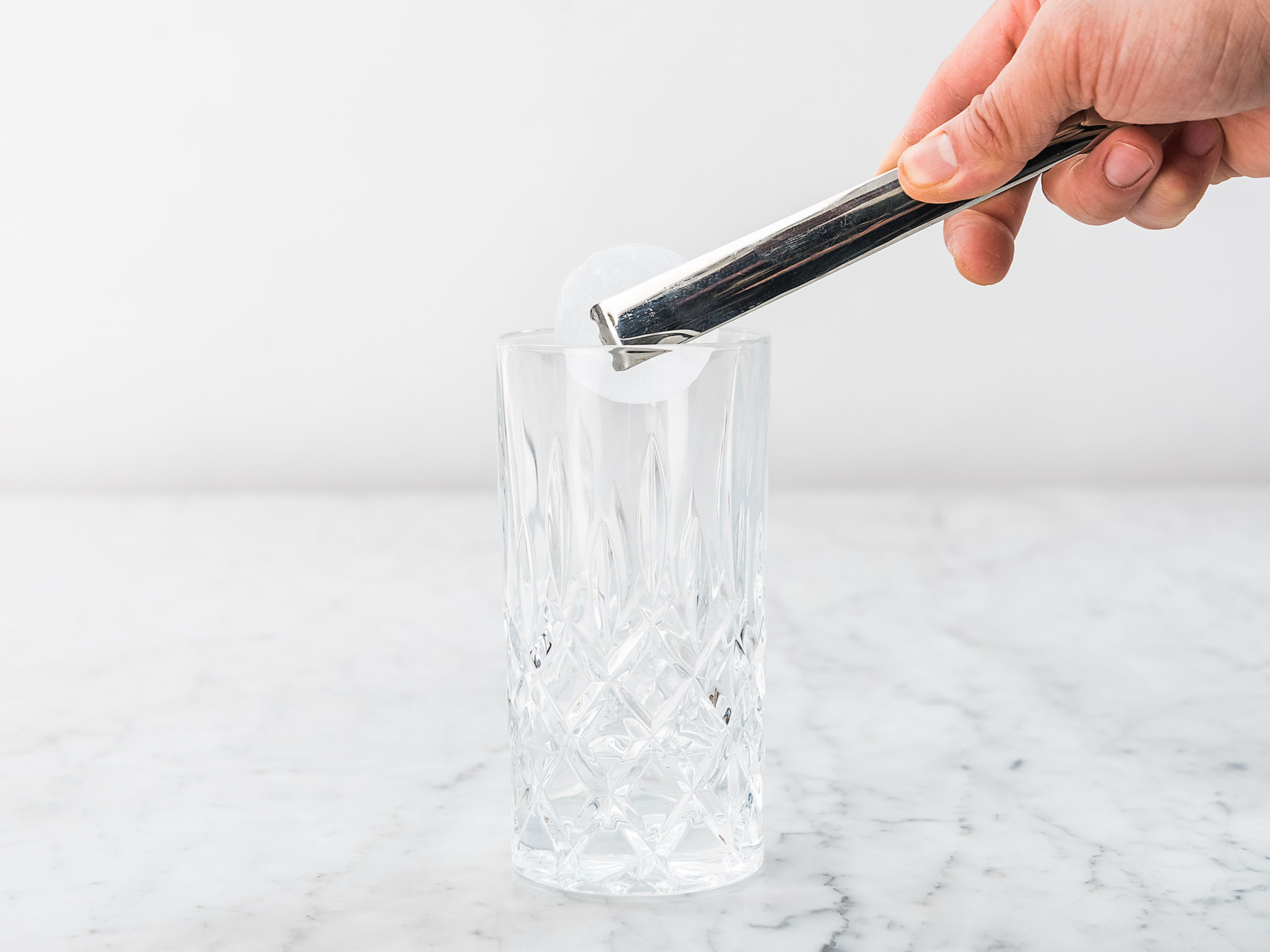 Gin in ein Longdrinkglas füllen und Eiswürfel dazugeben.