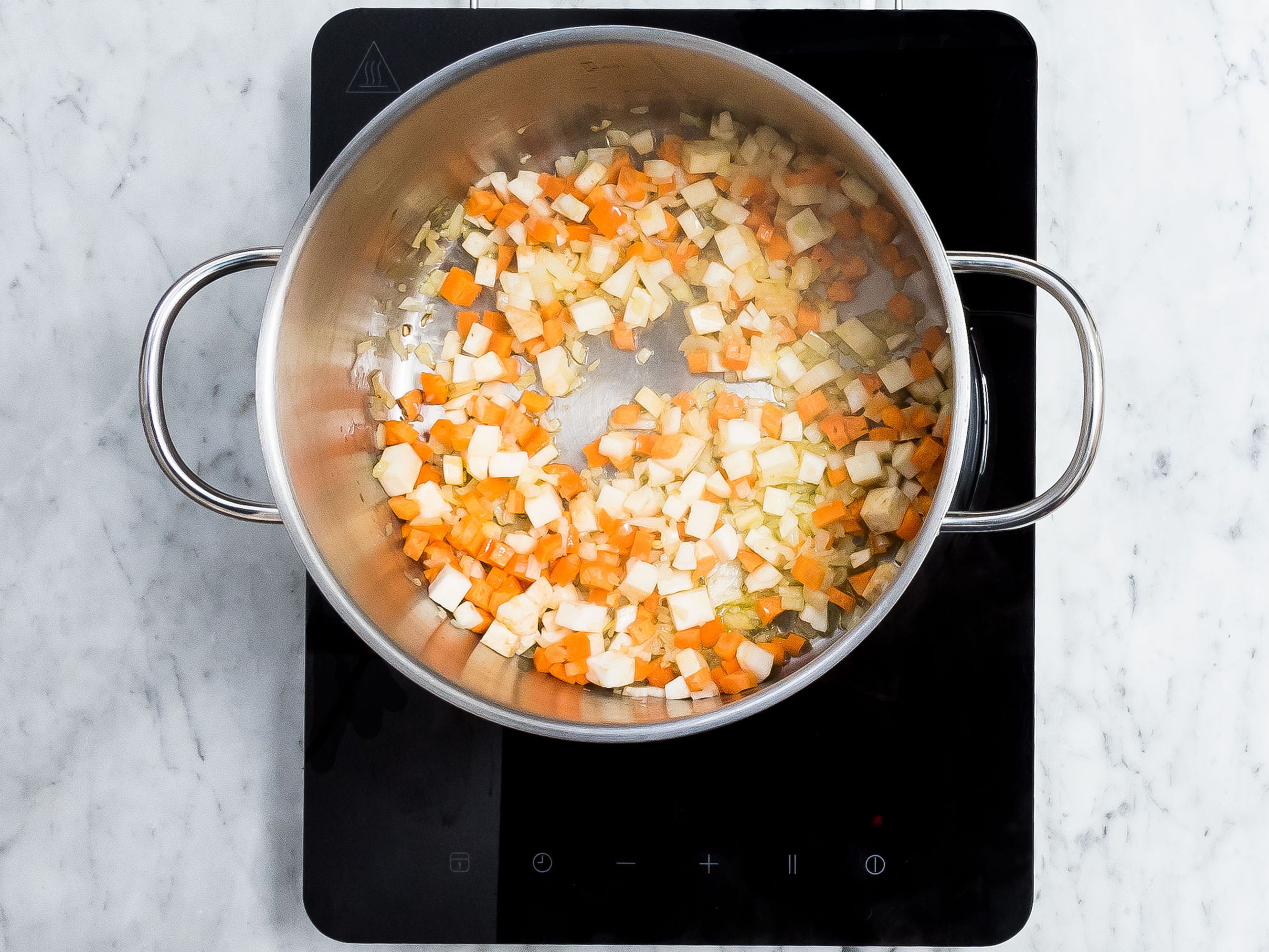 Peel and dice onion, carrot, parsley root, and celery root. Peel and finely crush garlic. In a large pot, heat olive oil over medium to high heat and add diced onion, carrot, parsley root, and celery. Sauté until golden brown, then add crushed garlic and sauté for 1 - 2 min. more.