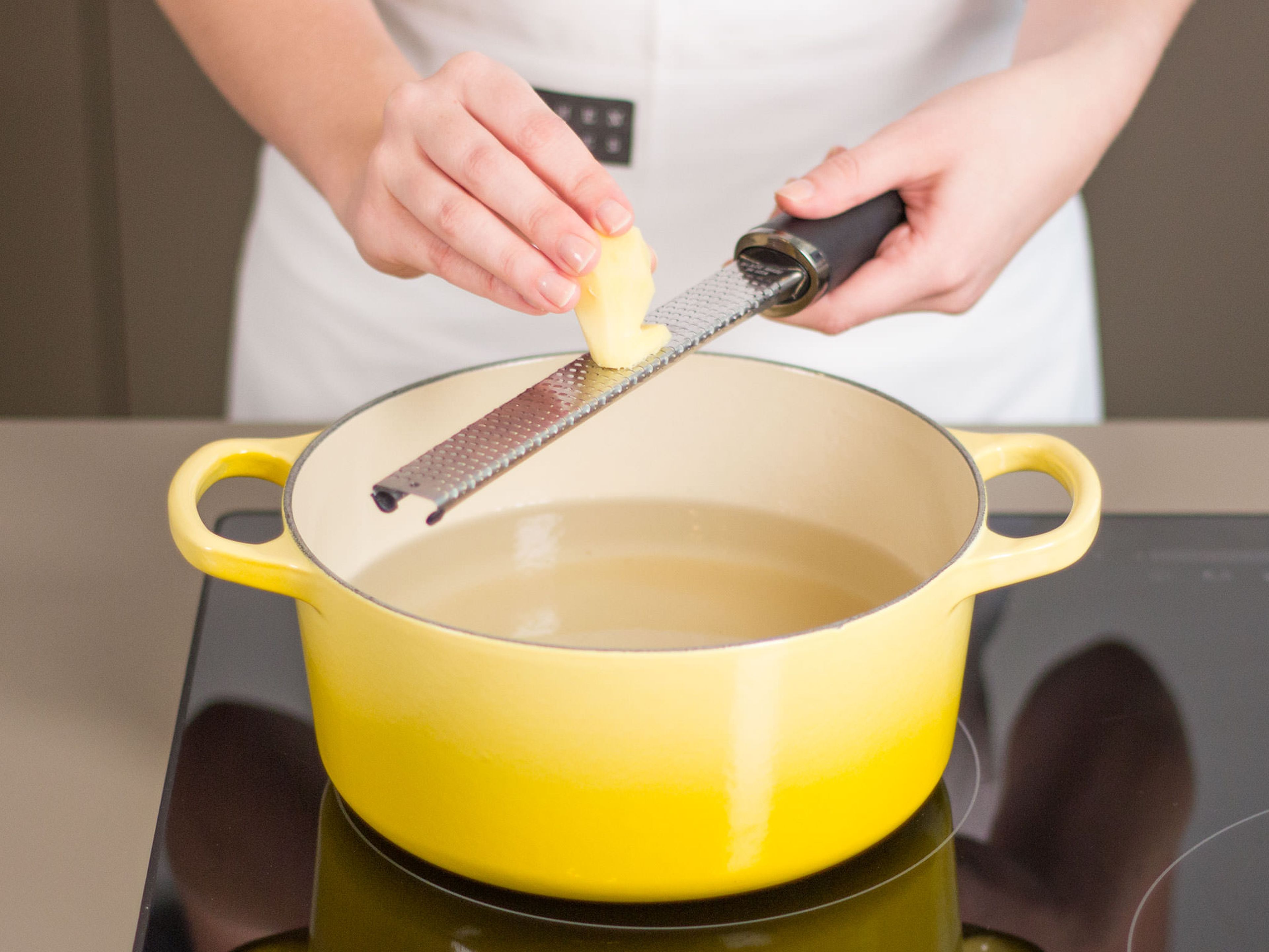 Wasser und Zucker in einem großen Topf bei starker Hitze zum Kochen bringen. Ingwer in den Topf reiben und ca. 1 – 2 Min. kochen.