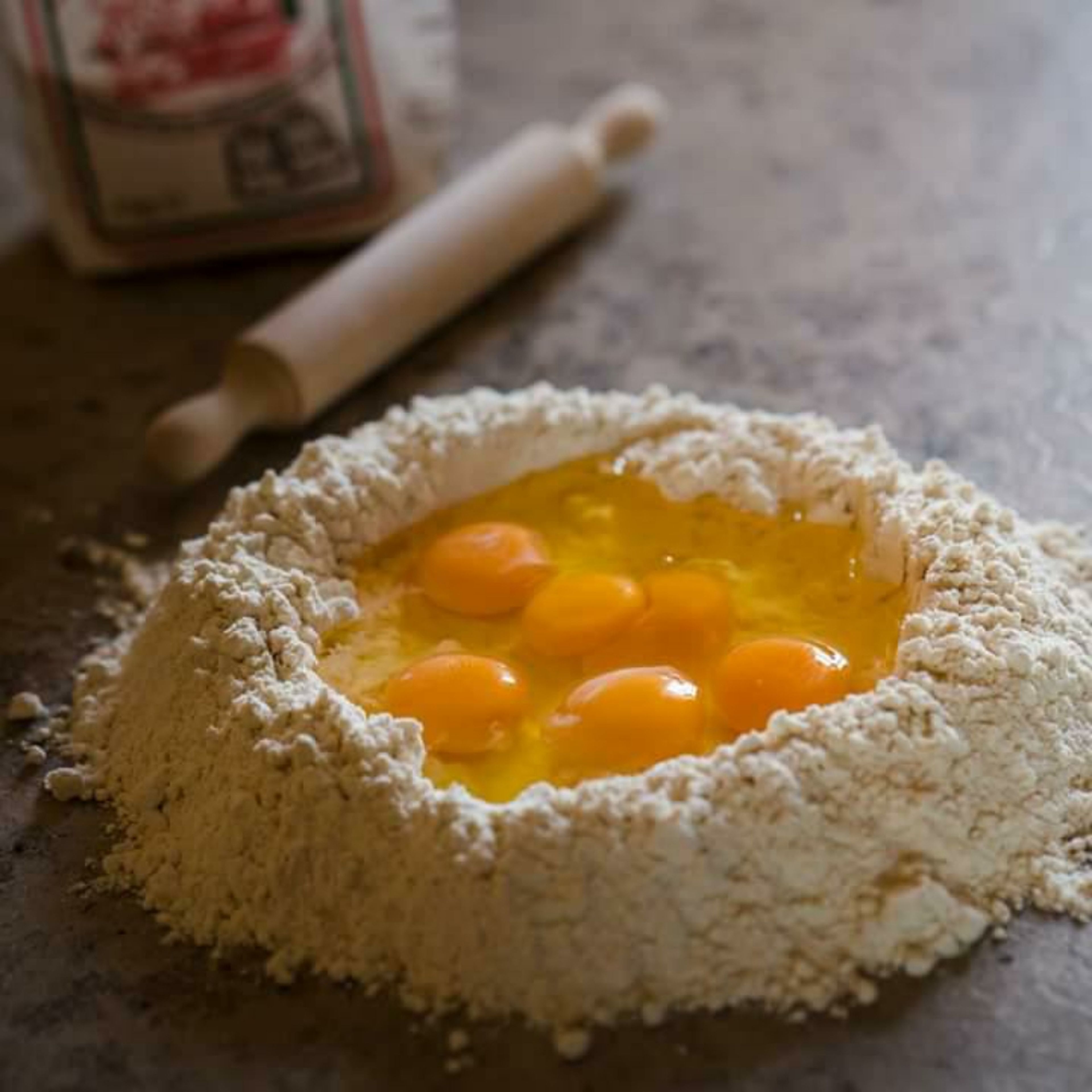 Die getrockneten Tomaten werden zuerst zu einer feinen Paste püriert. Anschließend auf einer sauberen Arbeitsfläche das Mehl mit den Eiern und dem Tomatenpüree zu einem festen Teig verarbeiten. Wenn der Teig zu feucht ist, ggf. noch etwas Mehl hinzufügen. Sobald der Teig fertig geknetet wurde, zu einer Kugel formen und für eine Stunde in Frischhaltefolie gewickelt ruhen lassen.