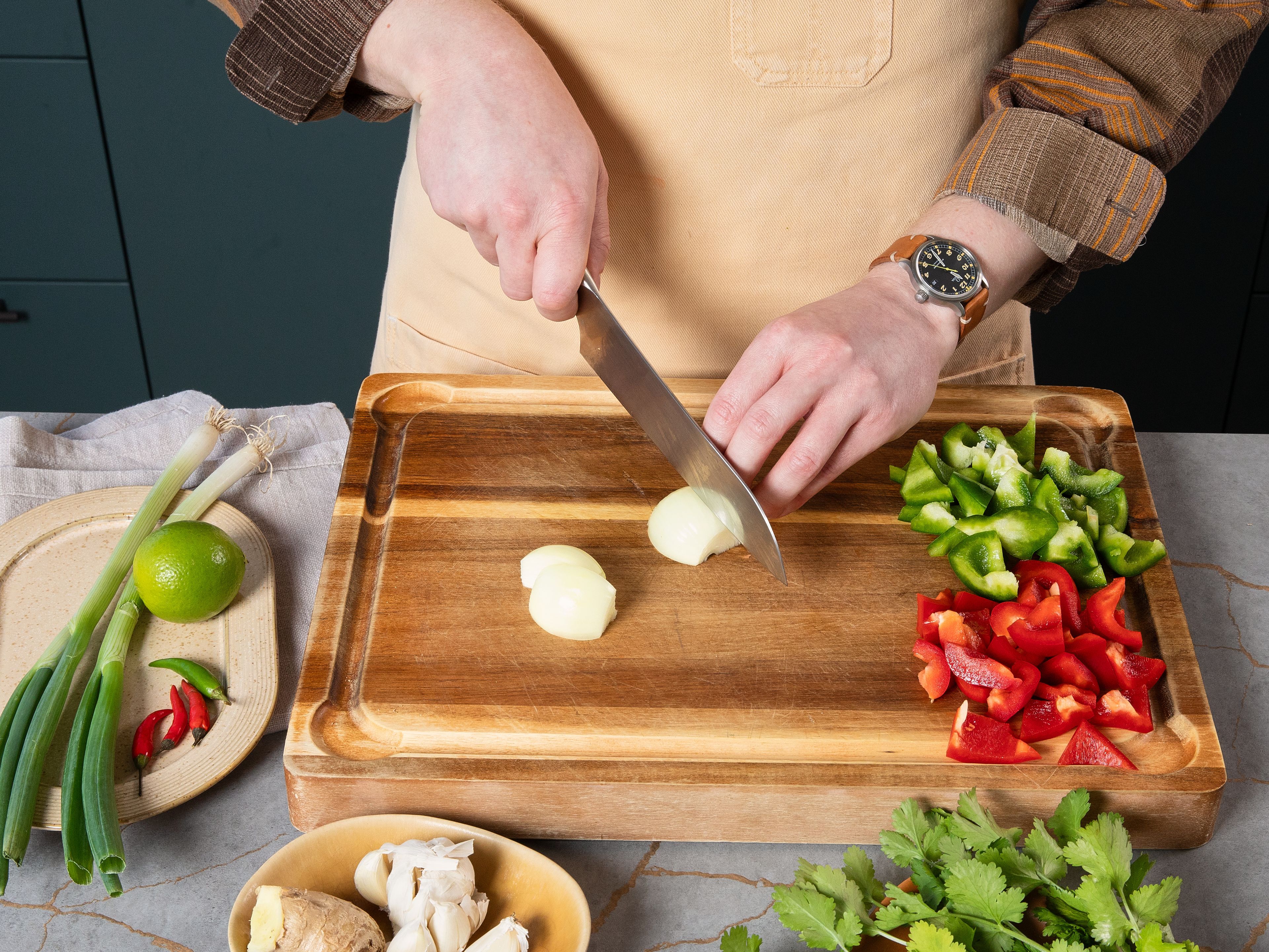 Chop onion into quarters and red and green peppers into approx. 2 cm/0,8 in. triangles. Peel and then finely slice garlic, and ginger. Finely slice thai chillies. Finely slice greens of spring onions and quarter whites lengthwise into approx. 4 cm/1,6 in. long pieces. Pluck coriander leaves and set aside, then finely slice stalks.