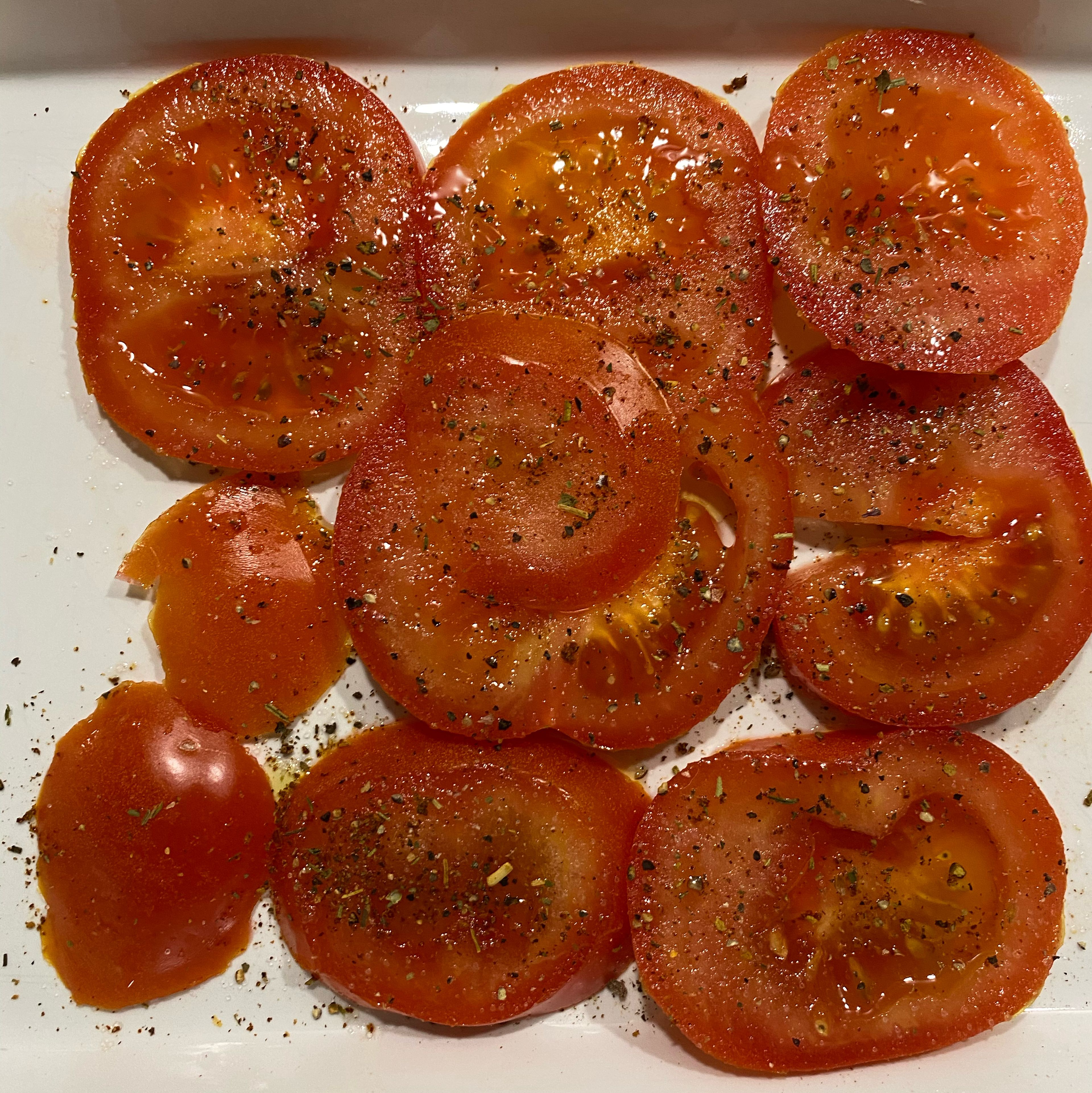 Tomaten und Büffelmozzarella in Scheiben schneiden und in einer Auflaufform schichten.