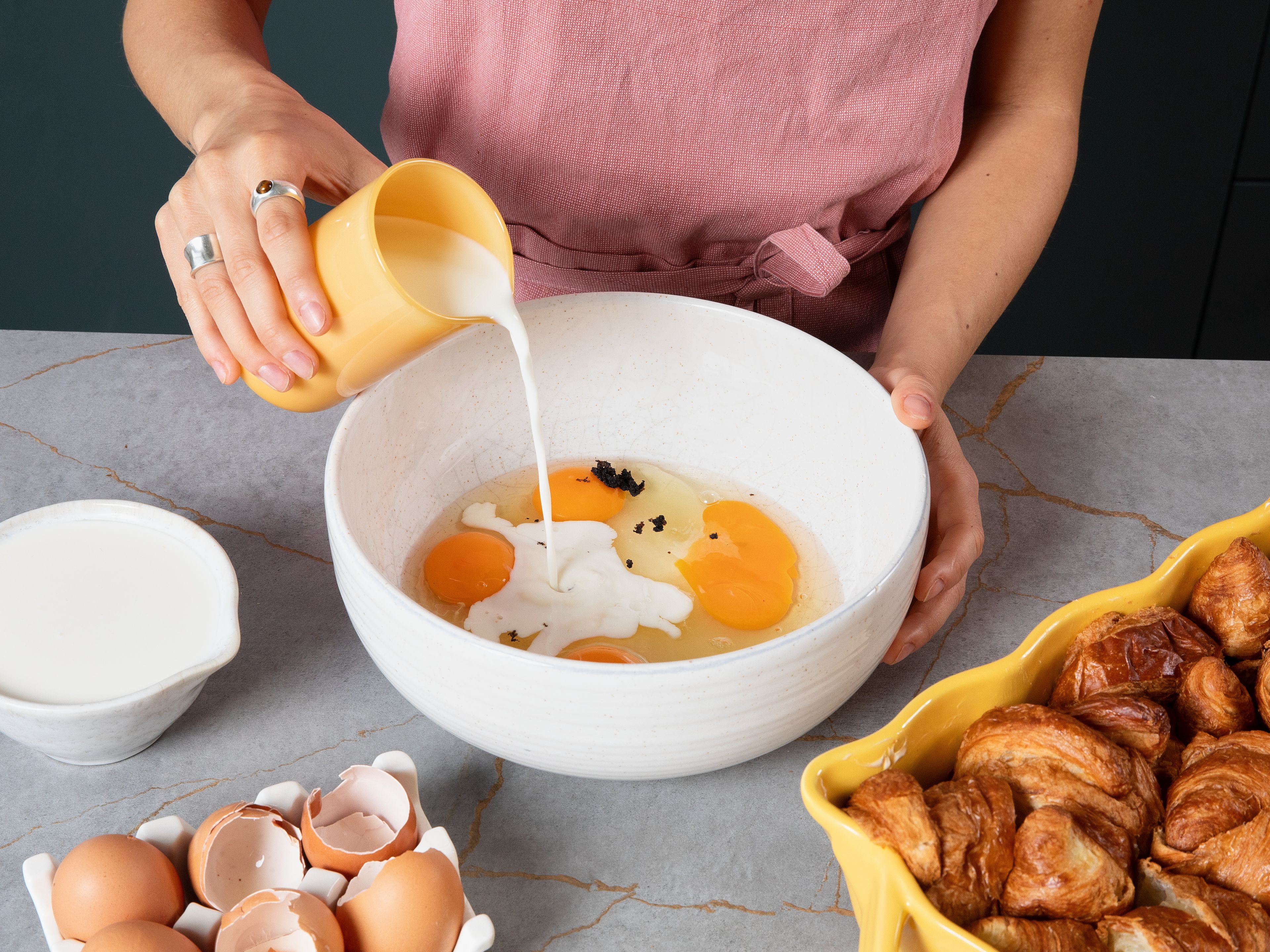 In einer großen Schüssel Milch, Eier, Sahne, Zucker, Vanillemark und Salz verrühren, bis sich der Zucker aufgelöst hat. Die Mischung gleichmäßig über die Croissants gießen, mit Alufolie abdecken und ca. 20 Min. (oder über Nacht) ziehen lassen, damit sich die Croissants gut vollsaugen können. Im vorgeheizten Ofen ca. 50–60 Min. mit der Folie abgedeckt backen, bis die Vanillecreme gestockt ist und die Croissants goldbraun sind. Für die letzten ca. 2 Min. der Backzeit die Alufolie entfernen, dabei den Auflauf im Auge behalten, da die Oberfläche schnell dunkel wird.