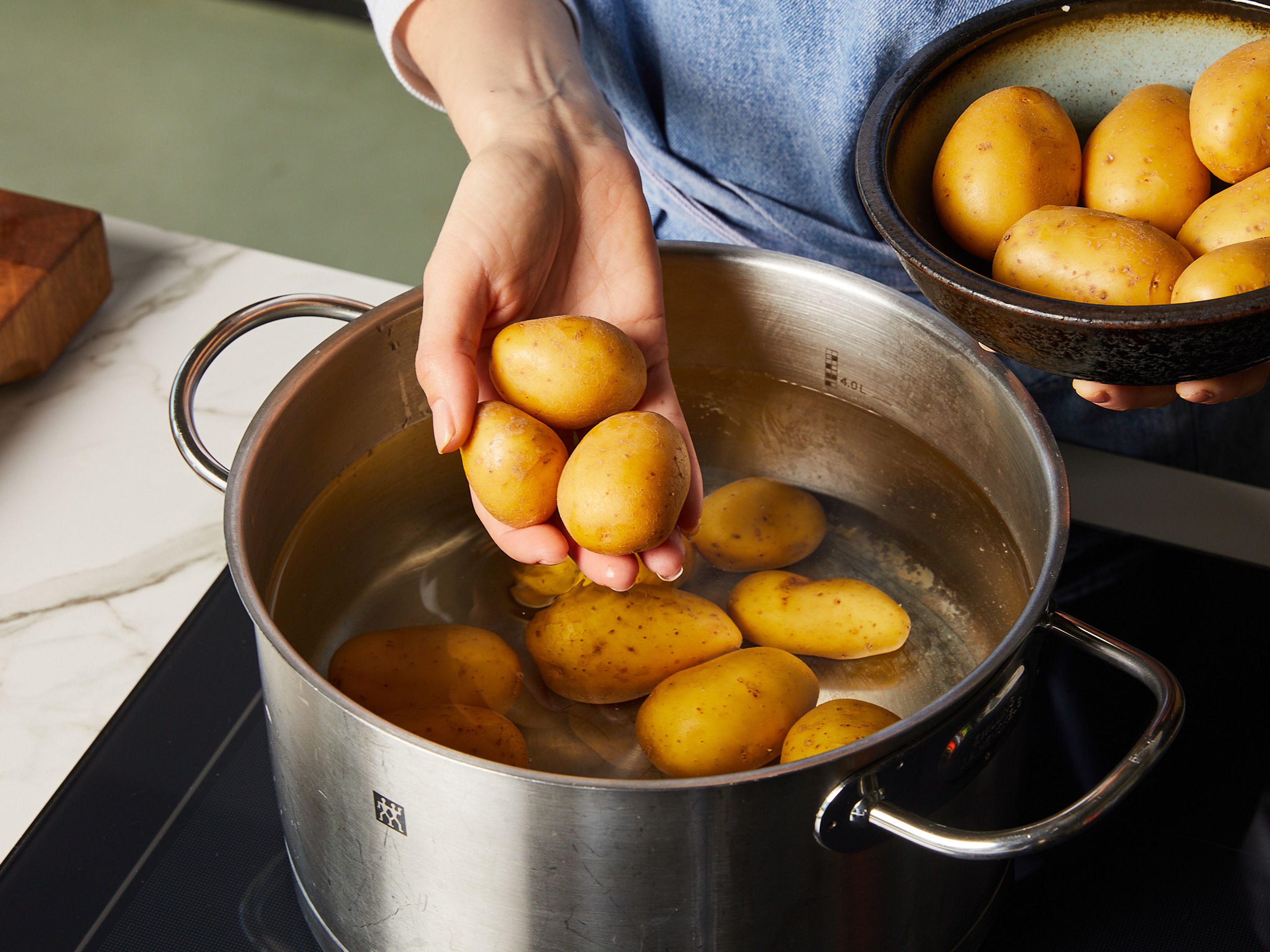 Preheat the oven to 200°C/392°F top/bottom heat. Place the potatoes in a large pot of salted water and bring to a boil. Then reduce the heat slightly and simmer, half-covered with a lid, for approx. 12–15 min. While the potatoes are cooking, cut the sugar snap peas diagonally into strips and finely dice the shallot. Drain the potatoes when you can easily pierce them with a fork.