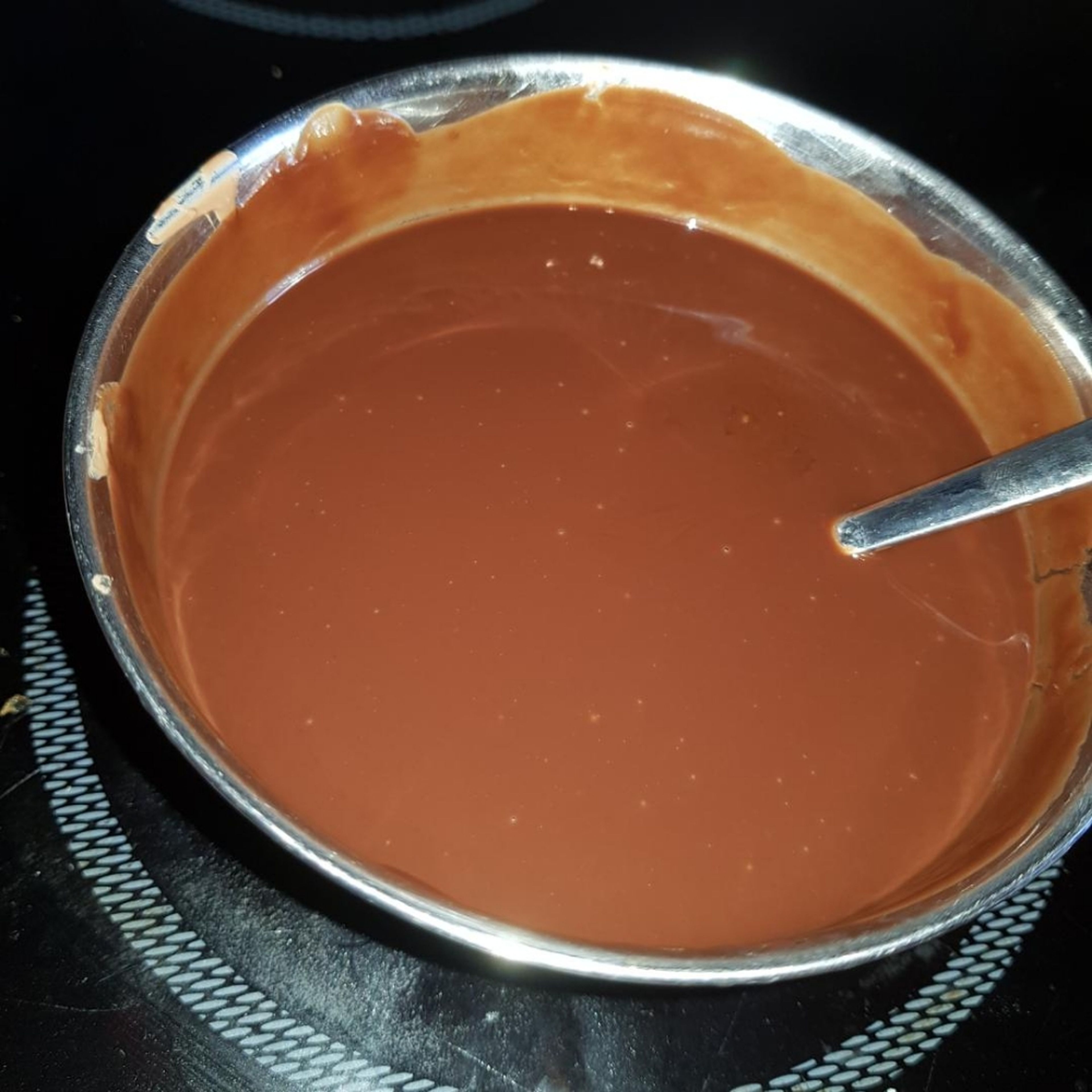 125g Vollmilchschokolade und 125g dunkle Schokolade mit der Butter und dem Wasser im Wasserbad erhitzen. Gelegentlich umrühren. Wenn die Mischung geschmolzen ist auf Raumtemperatur abkühlen lassen