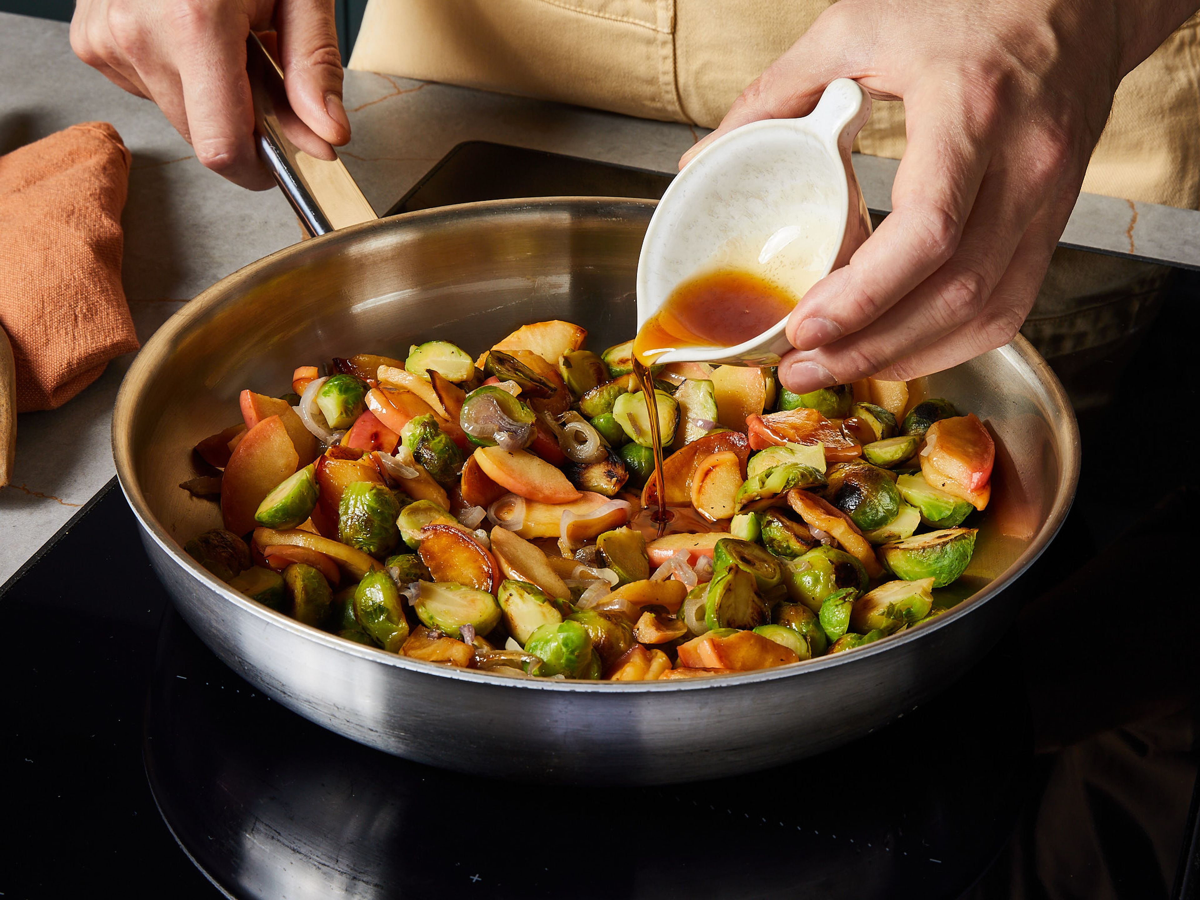 Den Apfel entkernen und in kleine bis mittelgroße Stücke schneiden. Die Schalotte schälen und in dünne Ringe schneiden. Rosenkohl, Apfelstücke und Schalotte in einer großen Pfanne bei mittlerer Hitze anbraten und dabei mit etwas Salz würzen. Ca. 10–12 Min. braten, dabei gelegentlich umrühren, bis der Rosenkohl leicht gebräunt und der Apfel weich ist. Mit Ahornsirup ablöschen und in eine Auflaufform umfüllen. Die Pfanne auswischen und den Backofen auf 220 °C vorheizen.