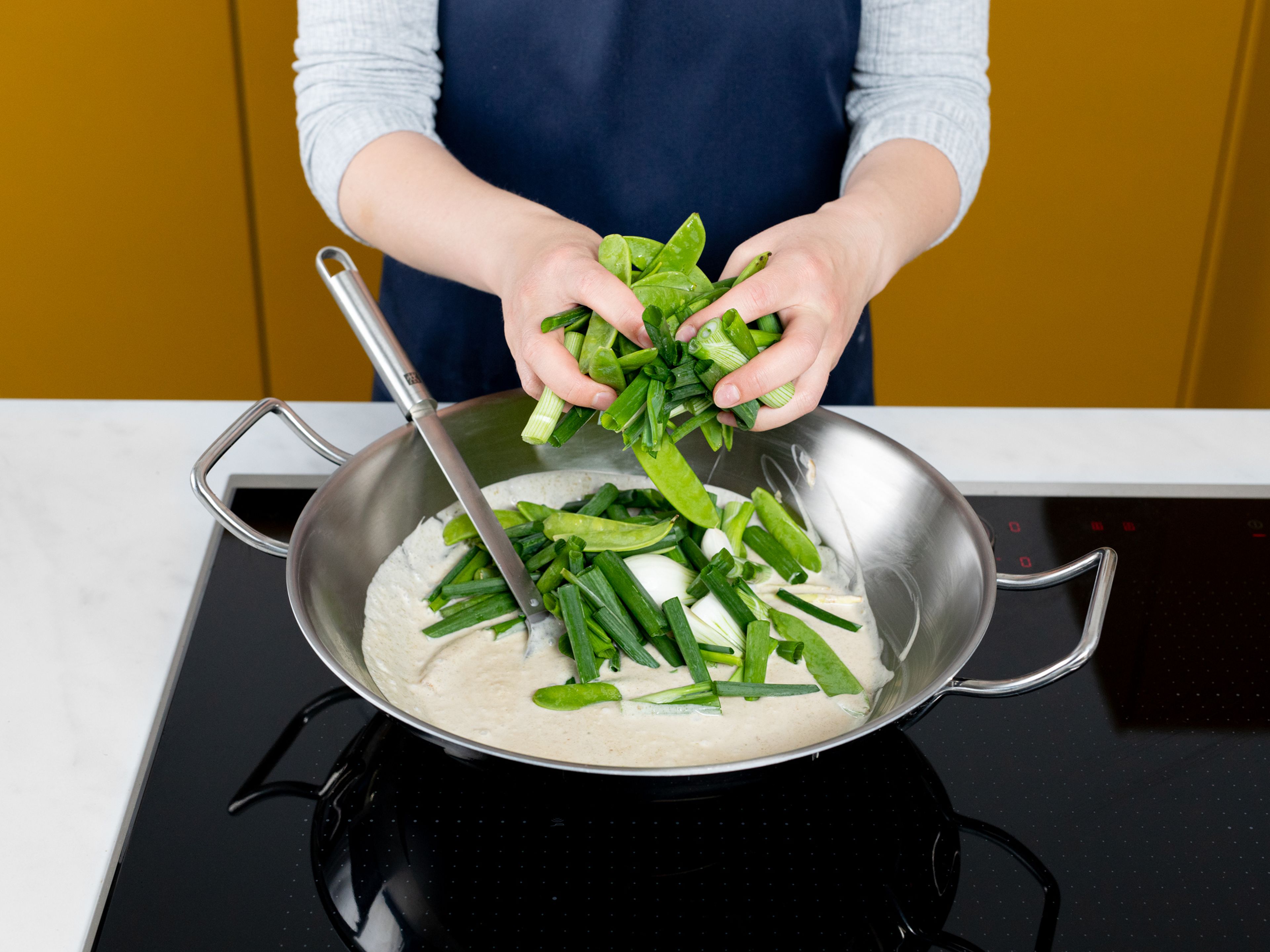 Heat coconut oil in a large pan and sauté garlic and lemongrass. Add green curry paste, cinnamon, and brown sugar, and let bloom for approx. 1 min. Deglaze with rice vinegar and coconut milk. Then add scallions and snap peas and continue cooking for approx. 1 min.