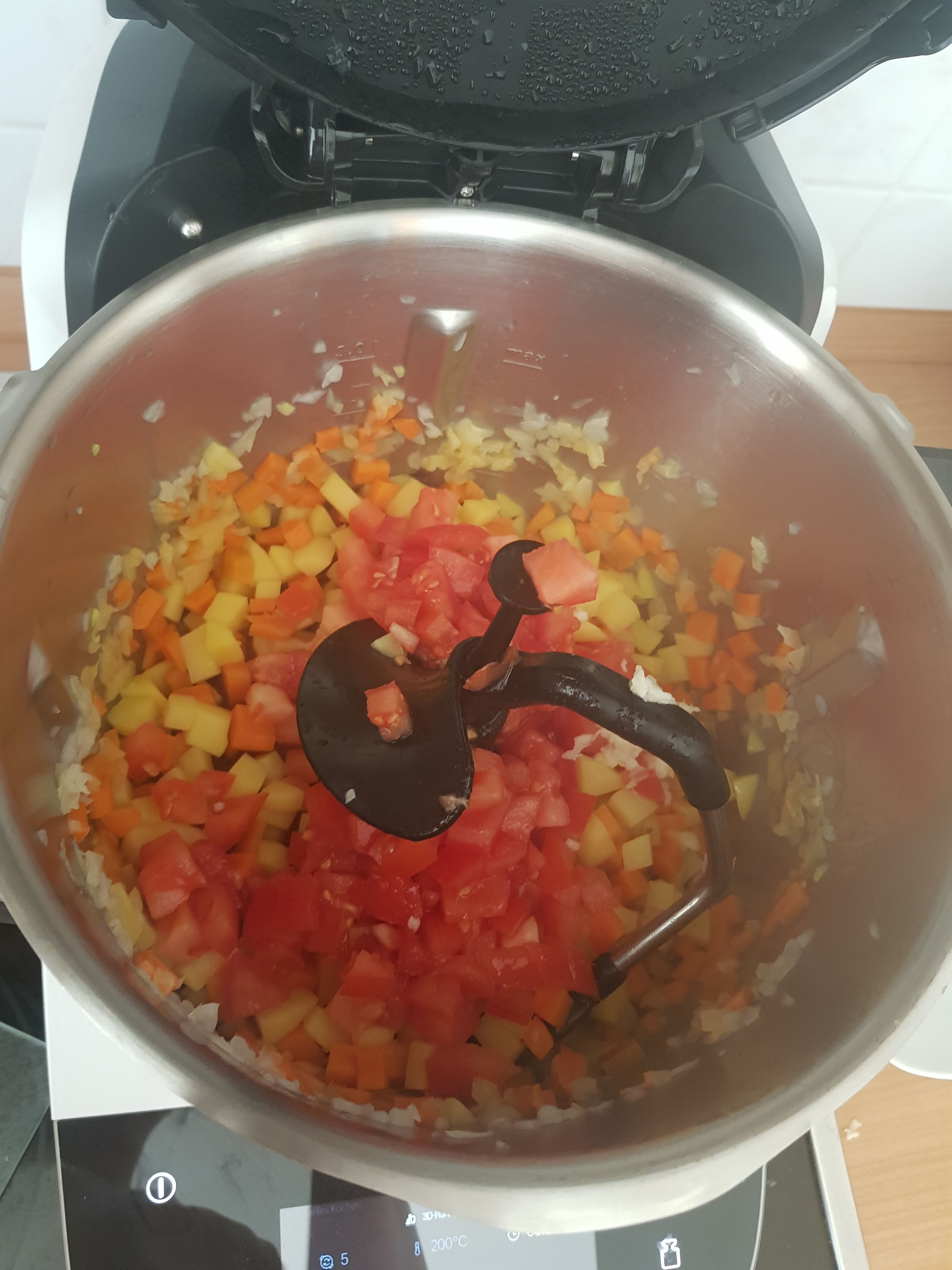 Danach die Tomaten und den Knoblauch (aus der Presse) mit in den Topf geben und bei geschlossenem Deckel, ohne Messbecher, weiter braten (3D-Rührer | Stufe 5 | 160°C | 4 Min.).