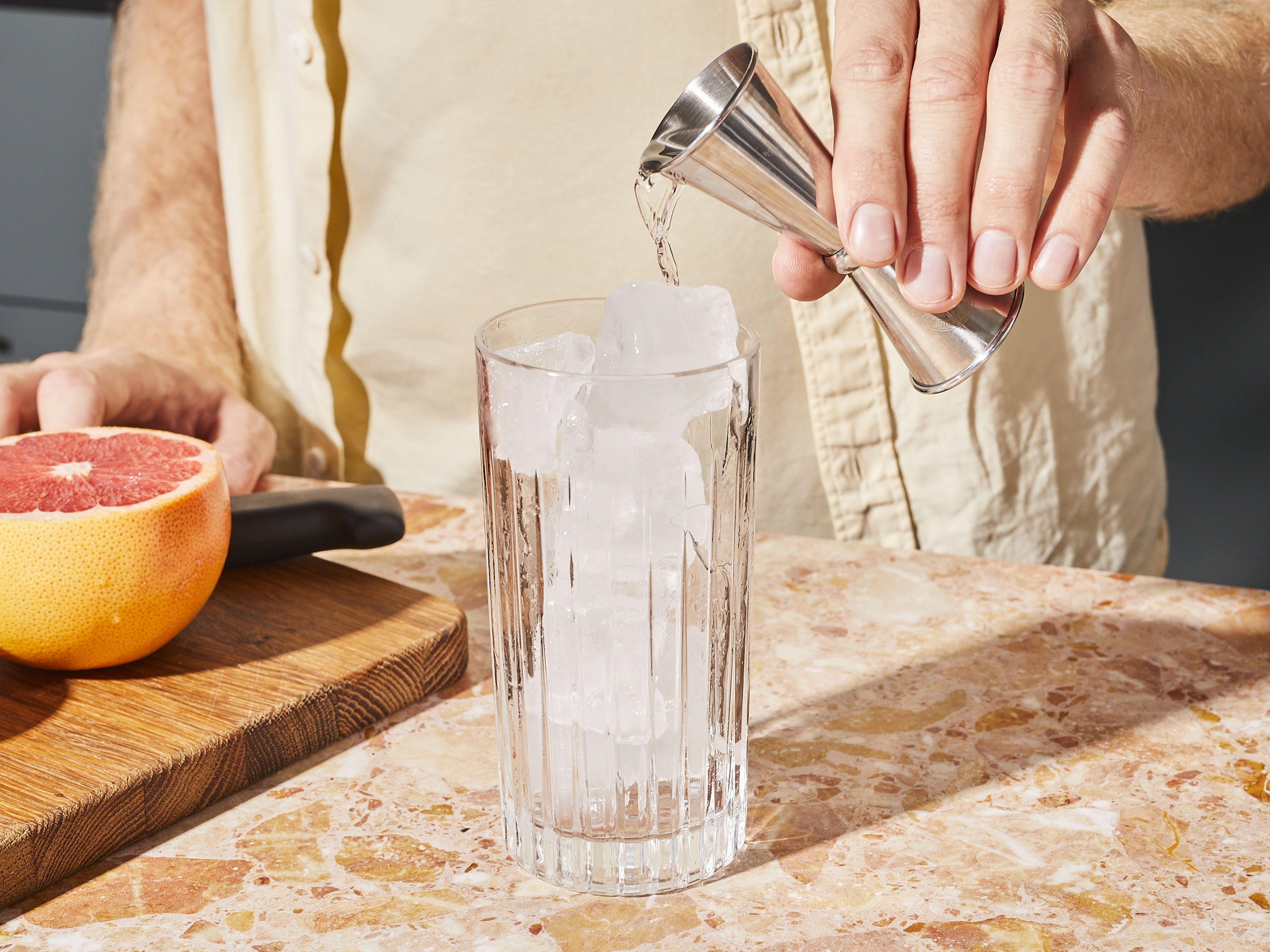 Ein Glas mit Eiswürfeln füllen und Gin hineingeben.