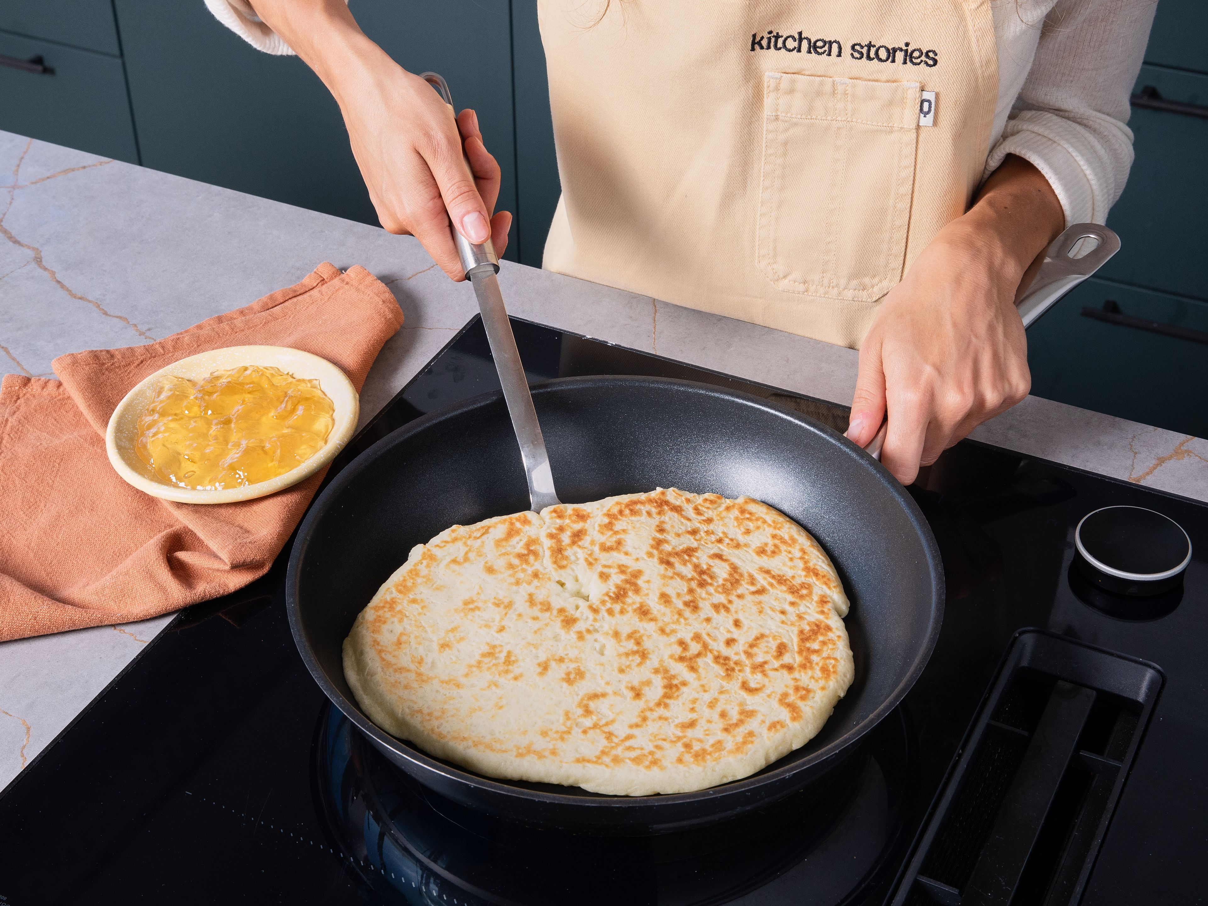 Den Ofen auf 200°C Ober-/Unterhitze vorheizen. Etwas Öl in eine beschichtete Pfanne geben und erhitzen. Das Fladenbrot in der Pfanne von beiden Seiten für jeweils ca. 1 Min. backen. Sobald der Teig Farbe annimmt und sich dunklere Flecken bilden, kann das Fladenbrot gewendet werden.