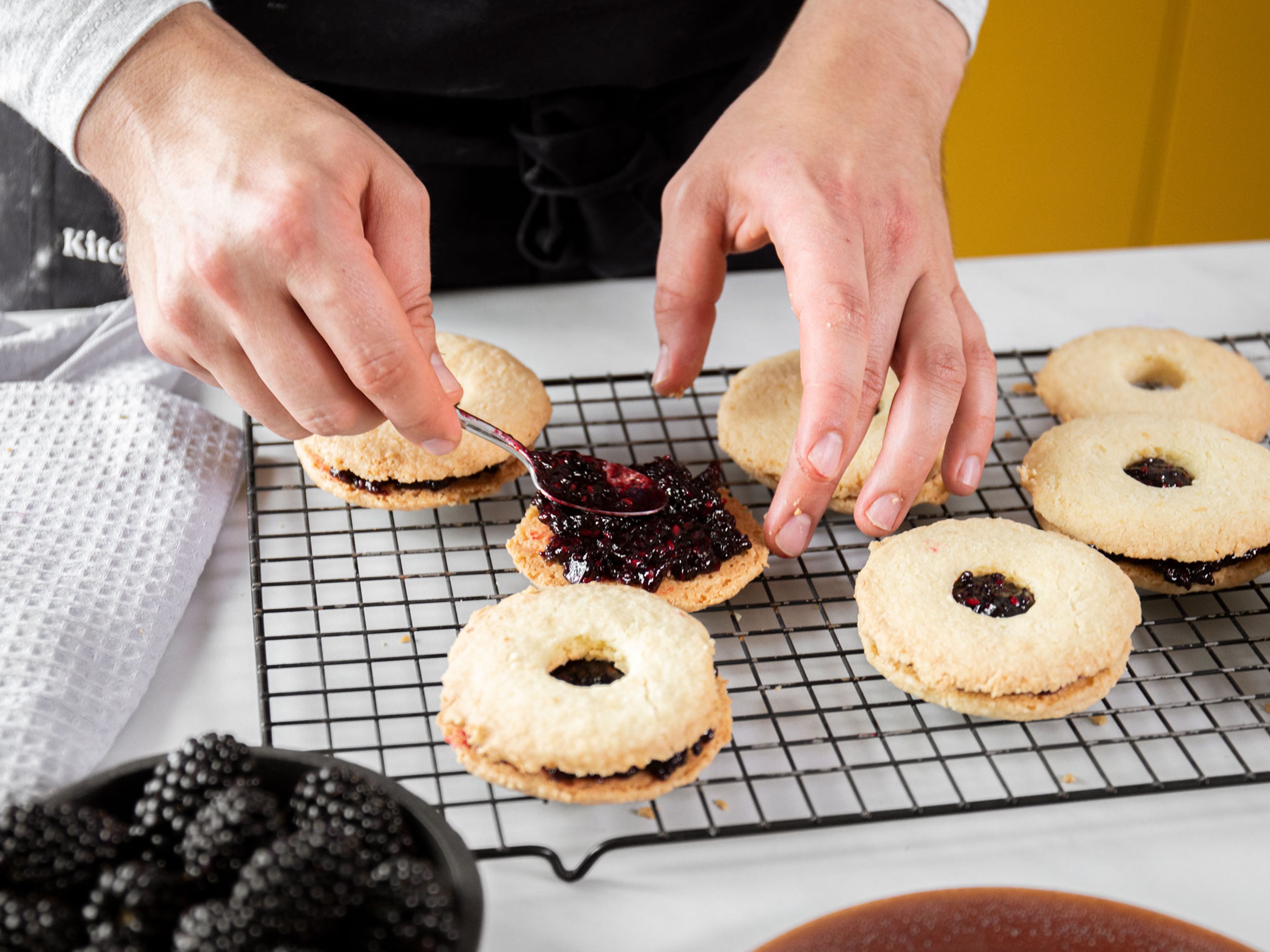 Add spoonfuls of blackberry jam to the full cookie rounds. Press a cut-out cookie round onto the top of each, twisting them on slightly to spread out the jam. Dust lightly with confectioner’s sugar and fill the holes of the cookies with one fresh blackberry, if desired. Enjoy!