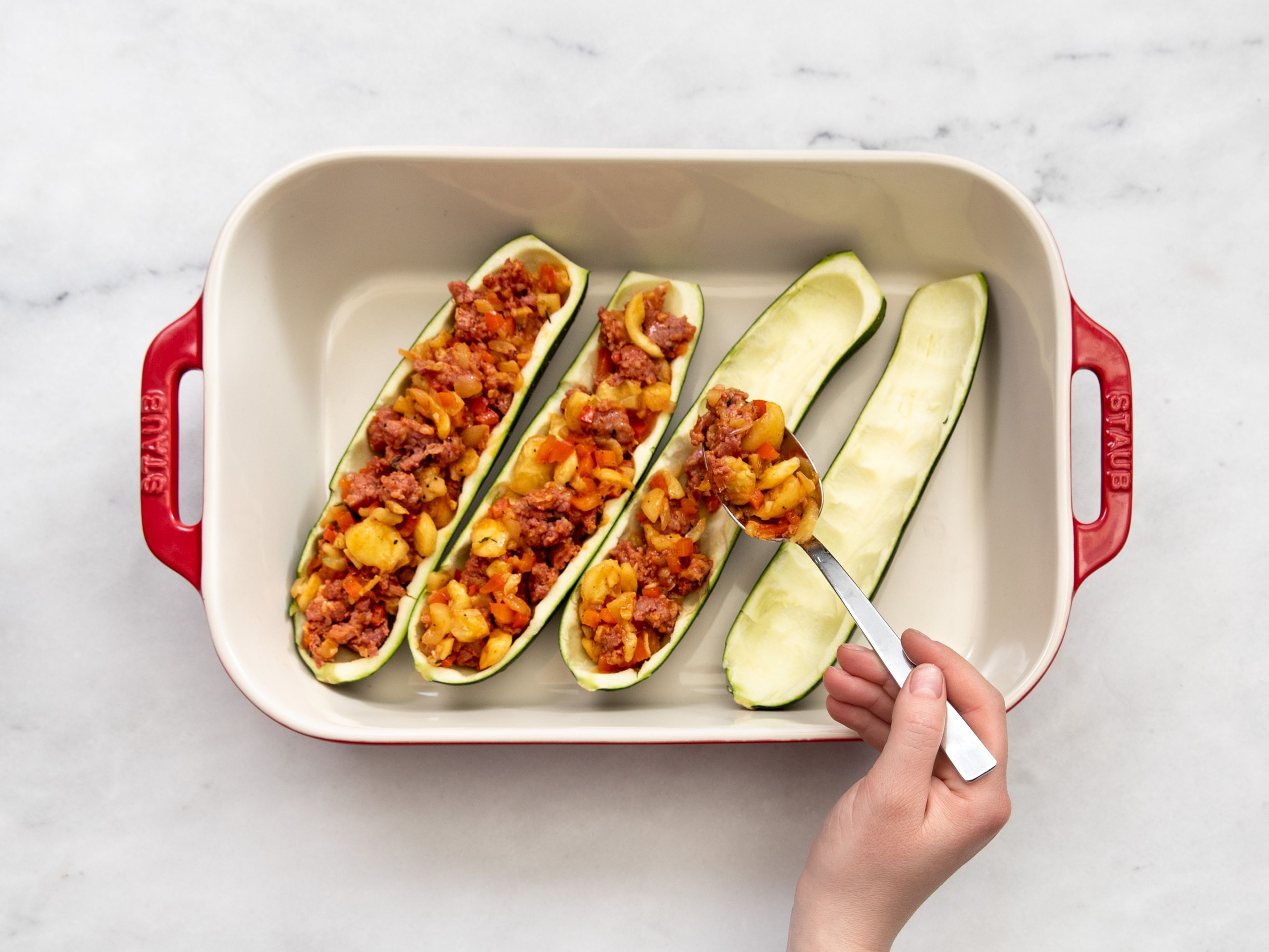 Place the zucchini in a baking dish and stuff them with the sausage and pepper filling. Generously sprinkle Parmesan breadcrumbs over the dish. Bake in the oven for approx. 25 min., or until the crust is golden brown and the zucchini is tender. Enjoy!