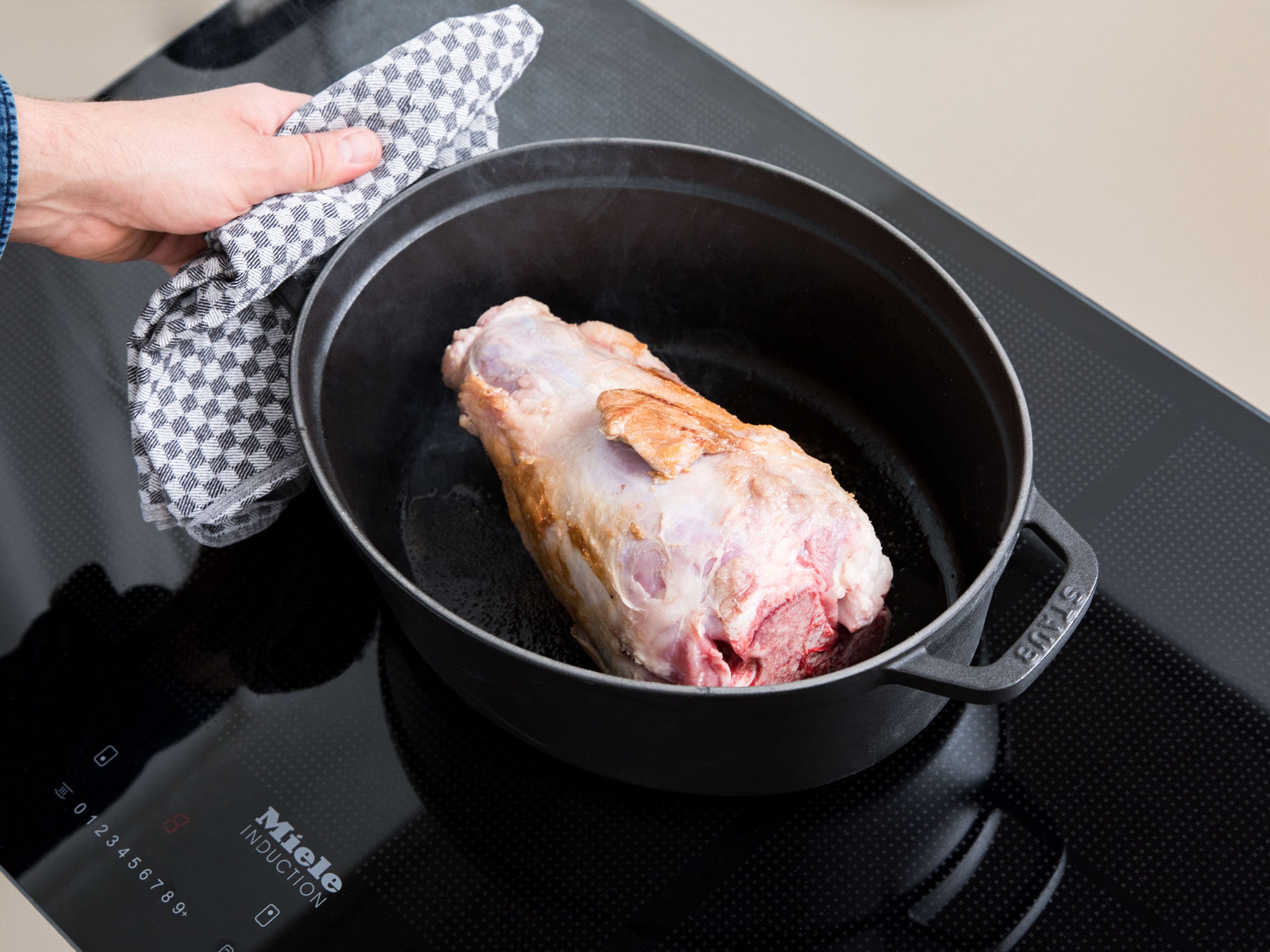 Heat oil in a heavy-bottomed ovenproof pot set over medium-high heat. Place the veal knuckle in the pot and fry on all sides until browned and golden. Next, add the chopped onions, garlic cloves, carrots, and celery and fry approx. 5 min.