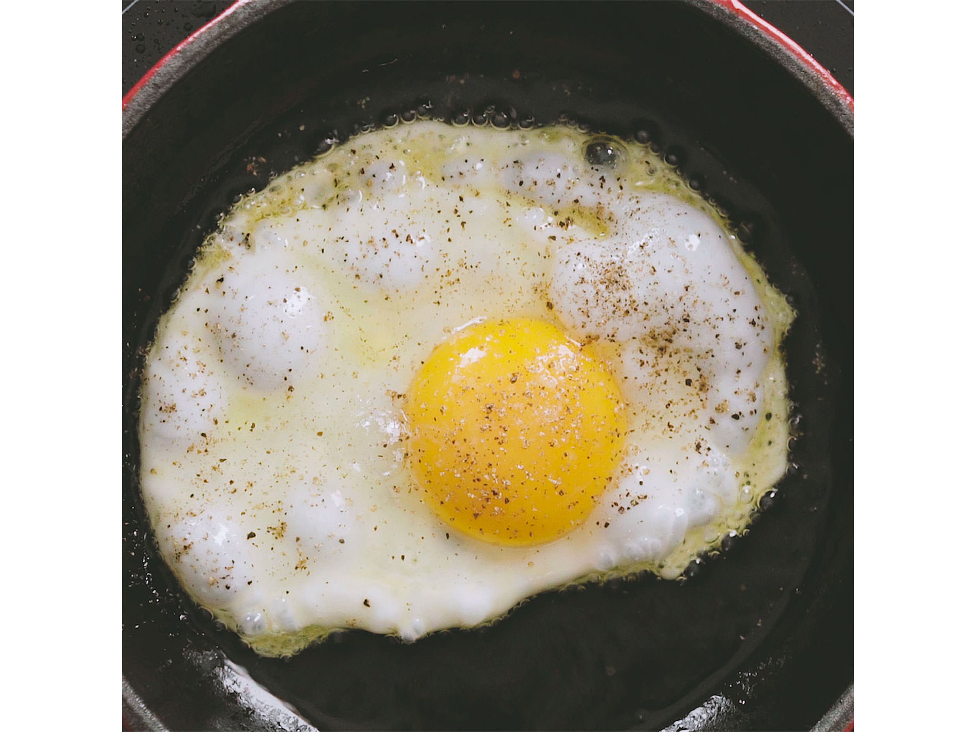 Olivenöl bei mittlerer Hitze in einer Pfanne erhitzen und das Ei braten. Spiegelei mit Salz und Pfeffer würzen.
