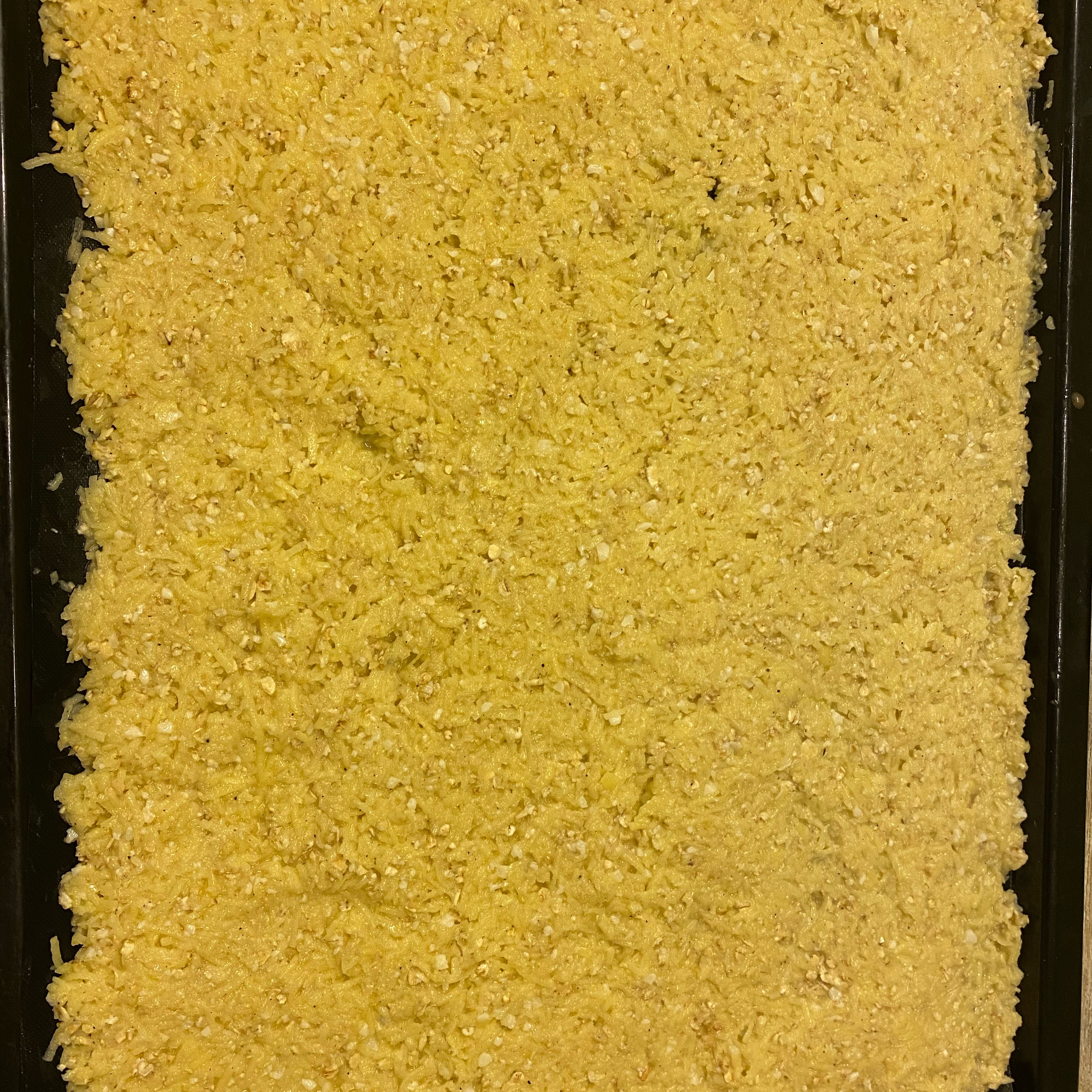 Das Cookit Universalmesser entfernen und die Masse auf ein mit Backpapier ausgelegtes Blech verteilen und glatt streichen.