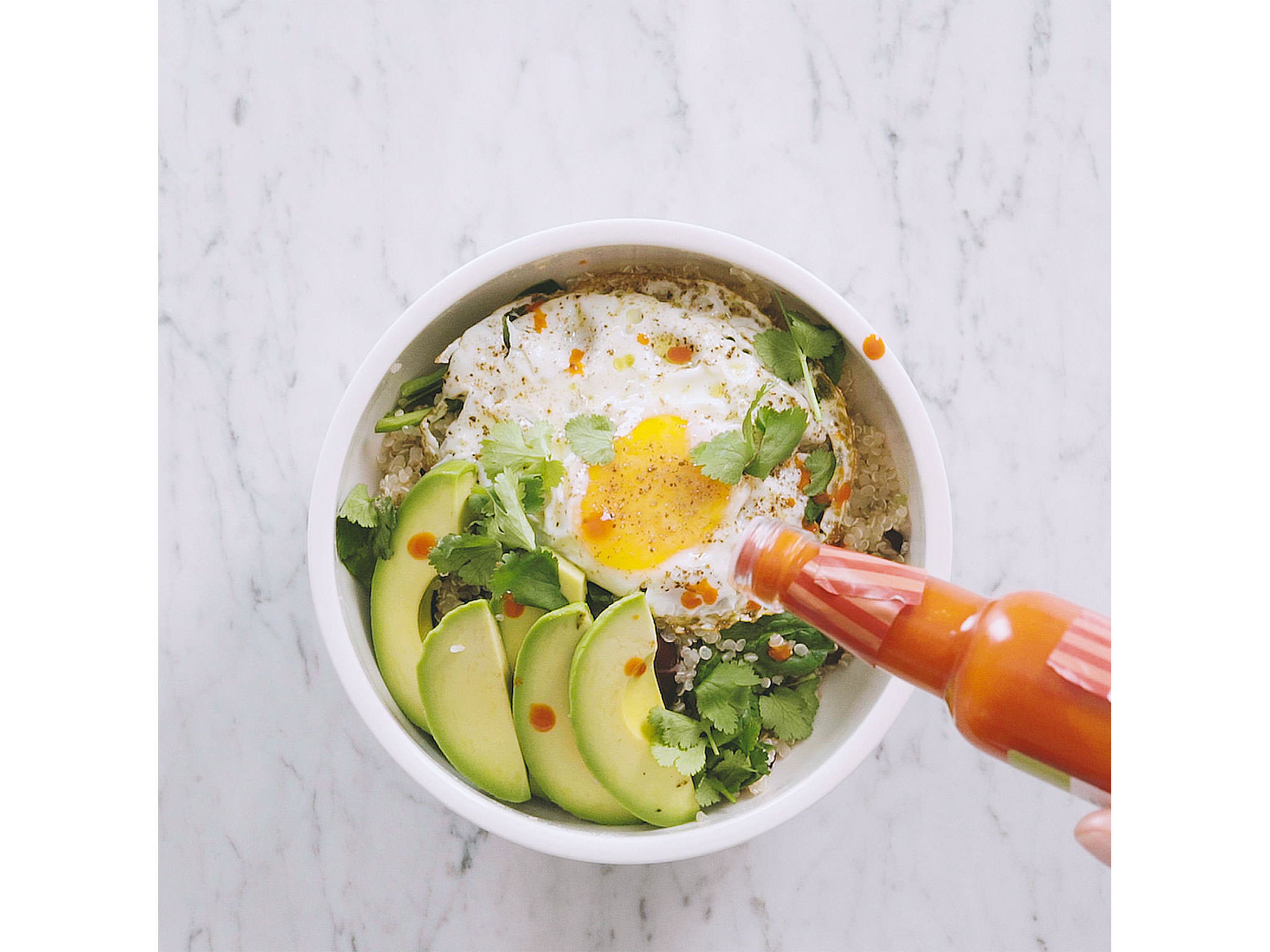 Remove garlic clove and cilantro stems from quinoa mixture and transfer mixture to a serving bowl. Top with avocado slices, fried egg, and cilantro leaves. Serve with hot sauce to taste.
